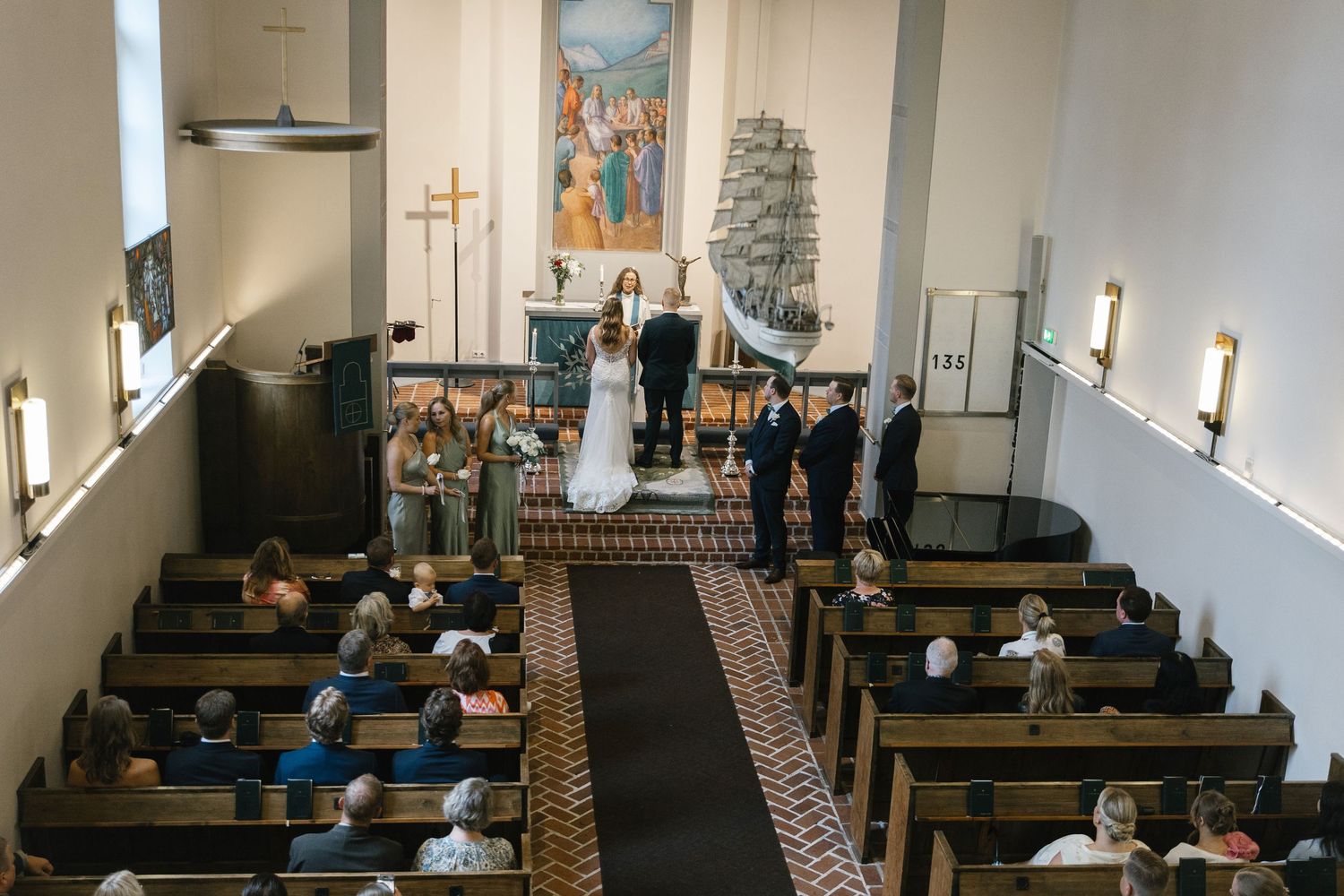 Interior view of a church sanctuary with wooden pews and religious artwork on the walls.