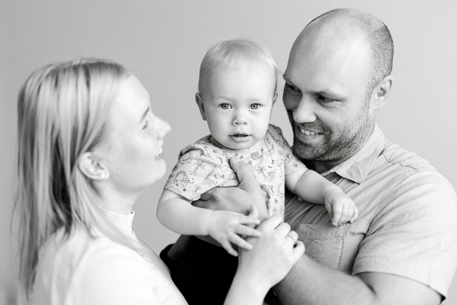 A black and white family portrait showing shared laughter and joy against a simple background.