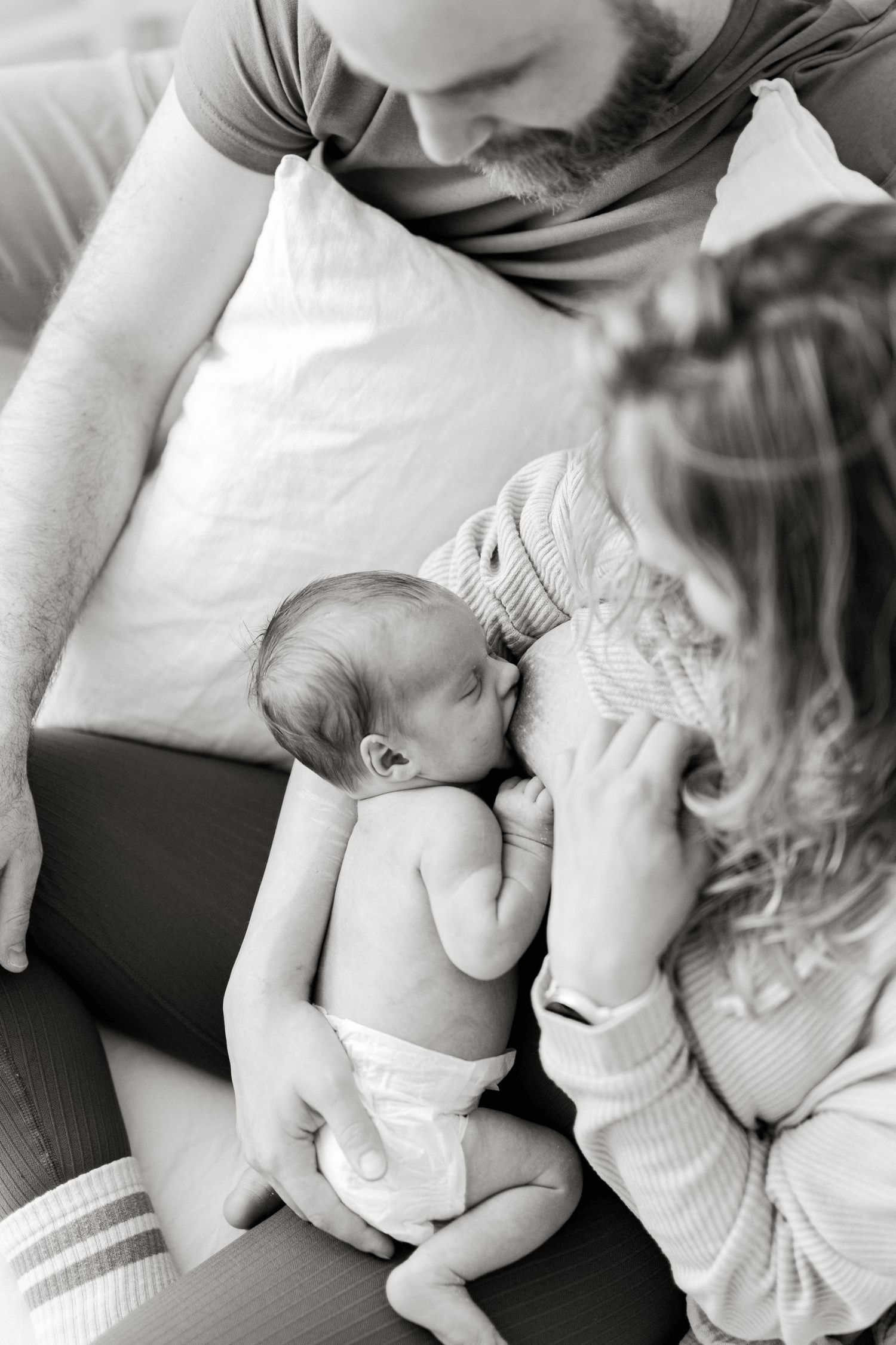 Family members tenderly holding and bonding with newborn baby in black and white series.