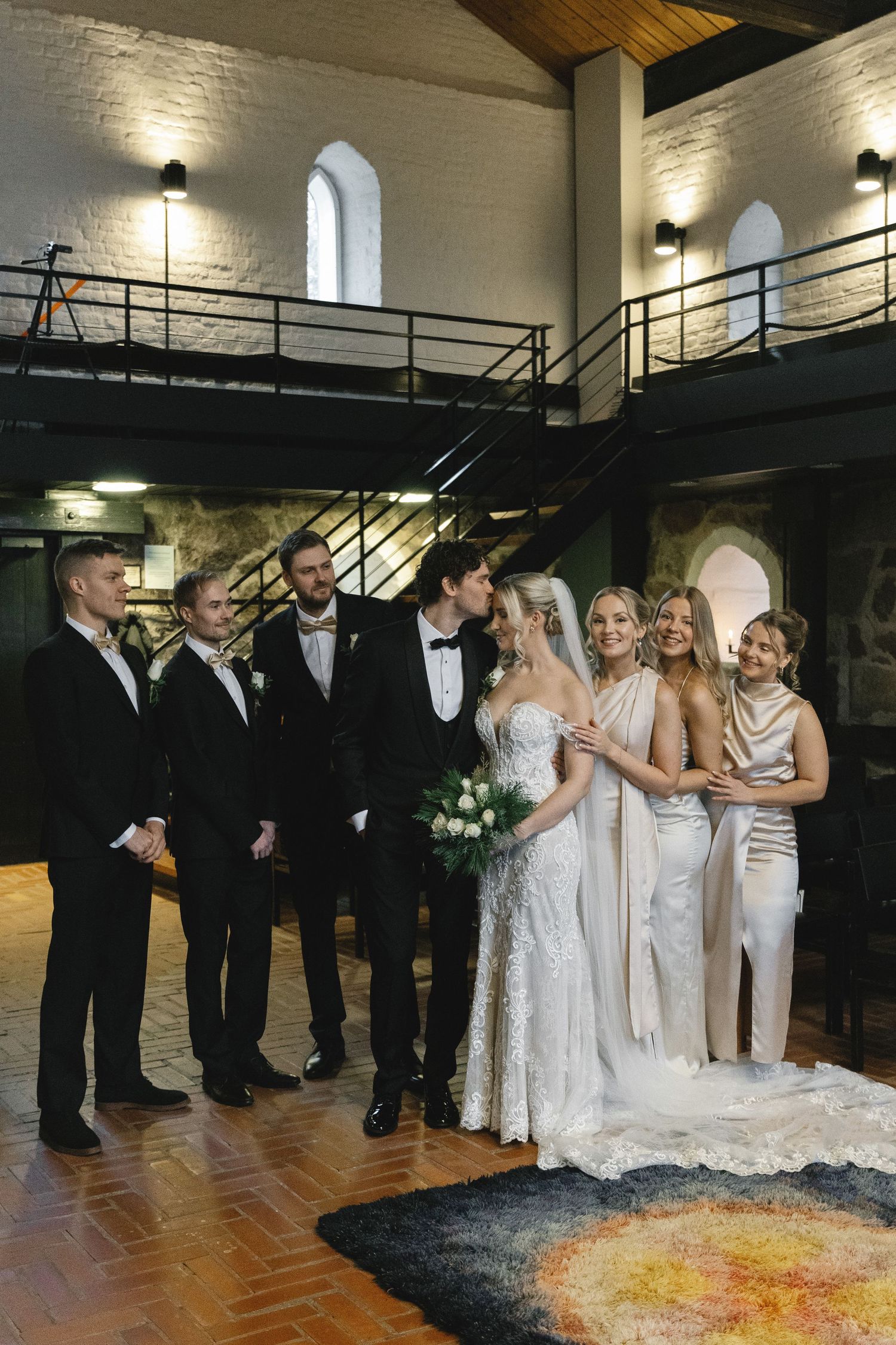 Wedding party posed in elegant church venue with dramatic lighting.