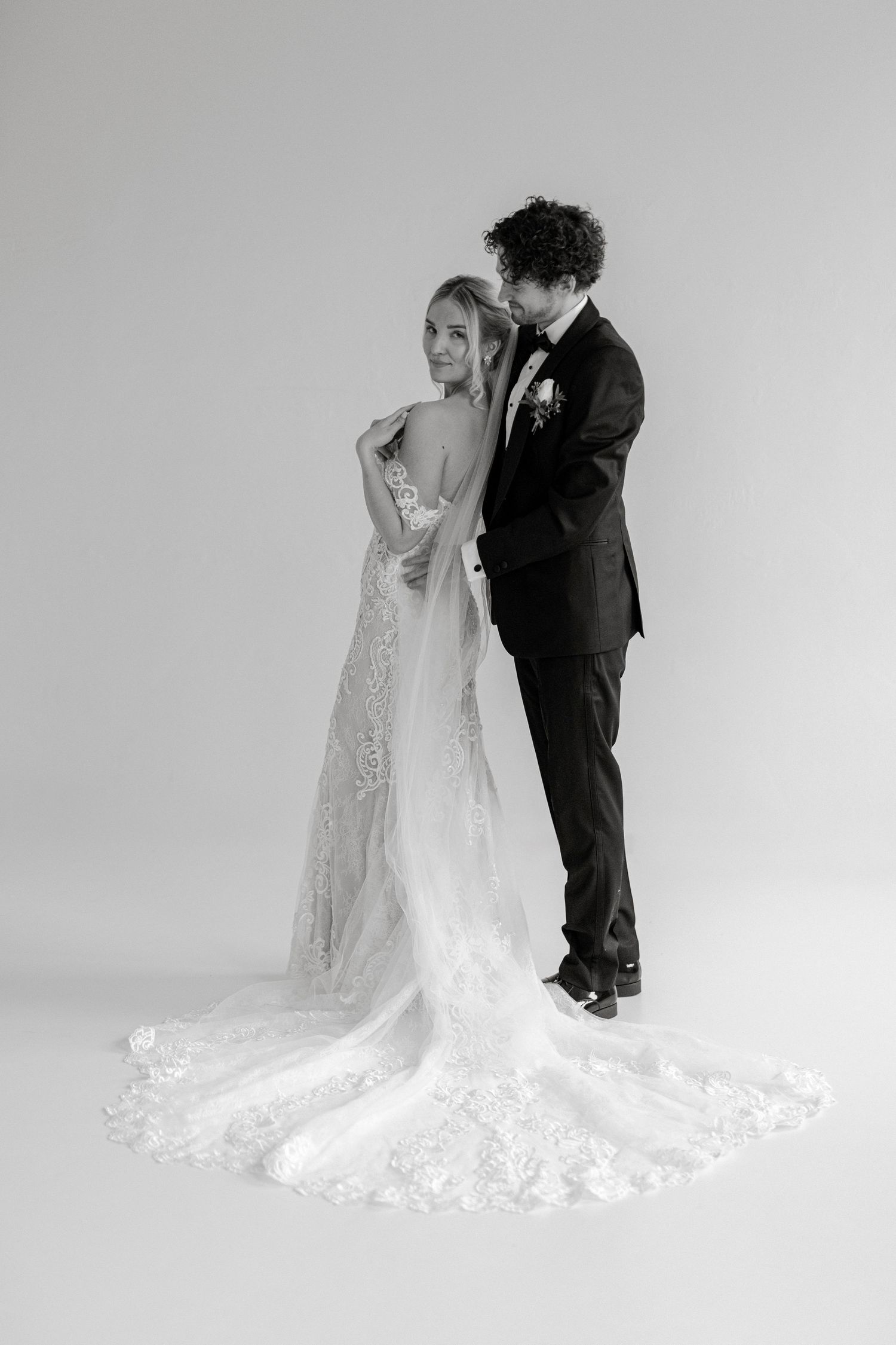 Black and white wedding photo of a couple with a stunning lace train on the bride's dress.
