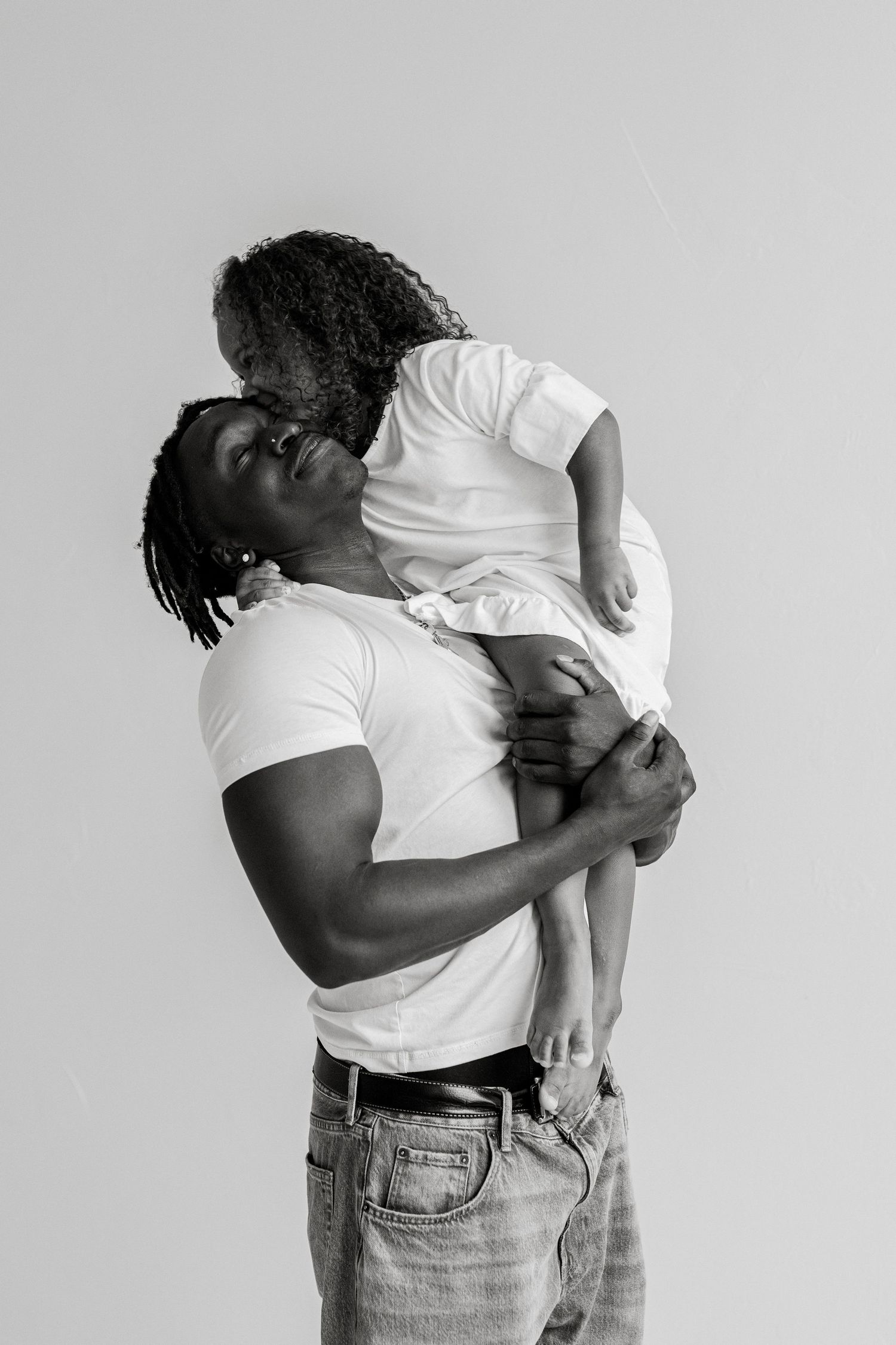 Tender black and white portrait of parent and child in matching white shirts.