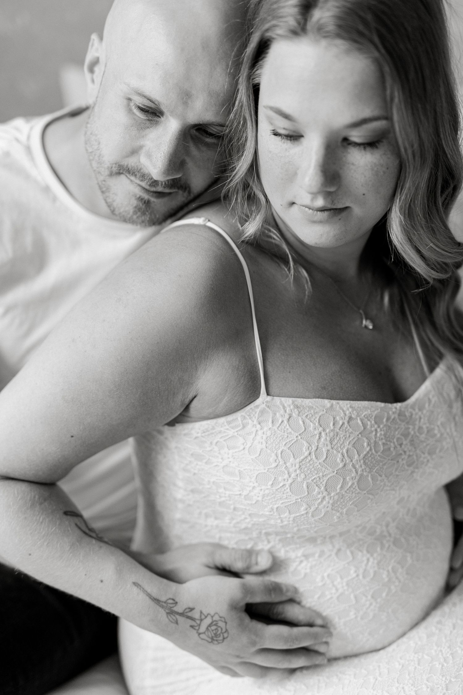 Black and white maternity photo of a couple tenderly cradling a pregnant belly, capturing an intimate moment.