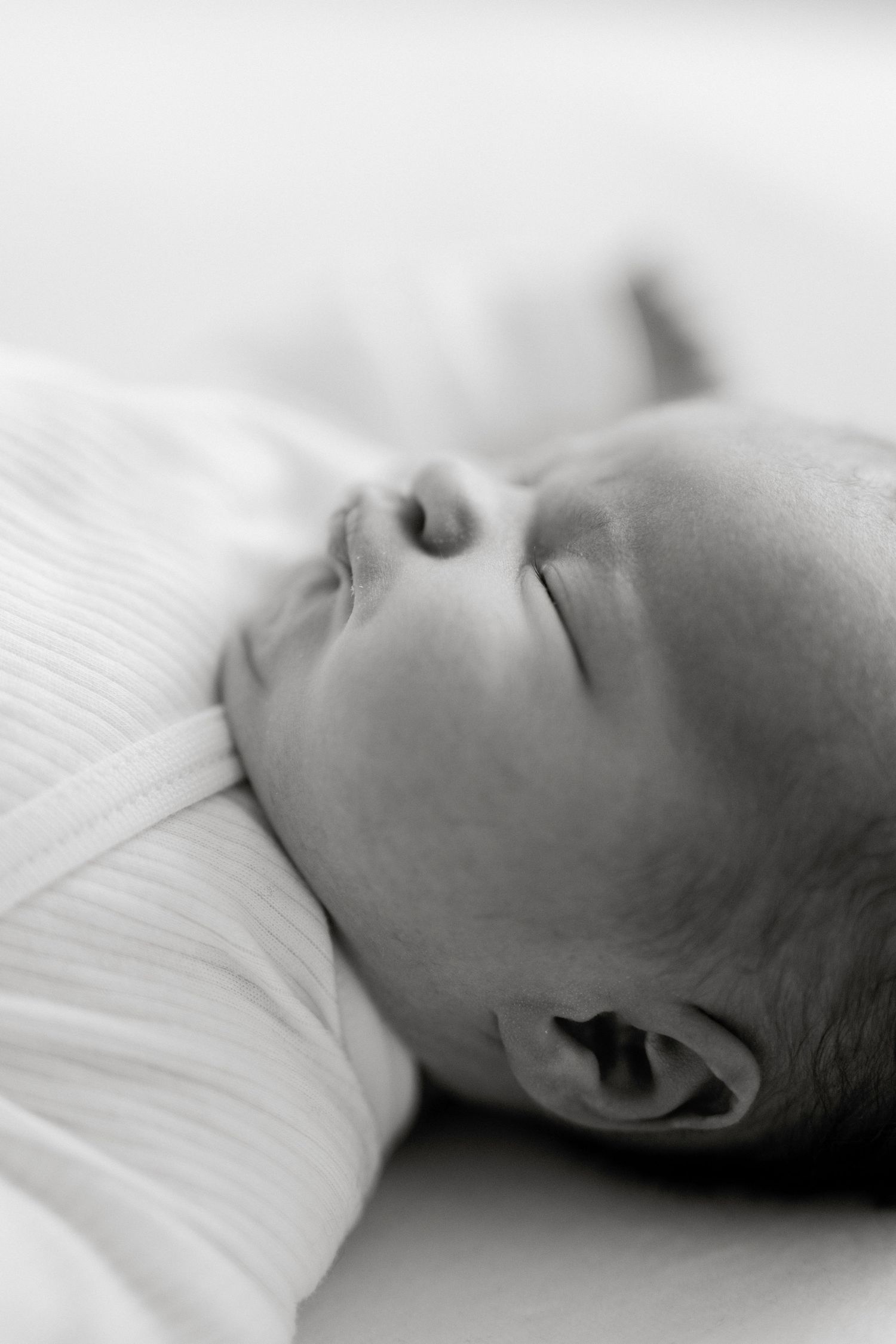 Black and white close-up profile shots of a sleeping infant's face against white bedding.