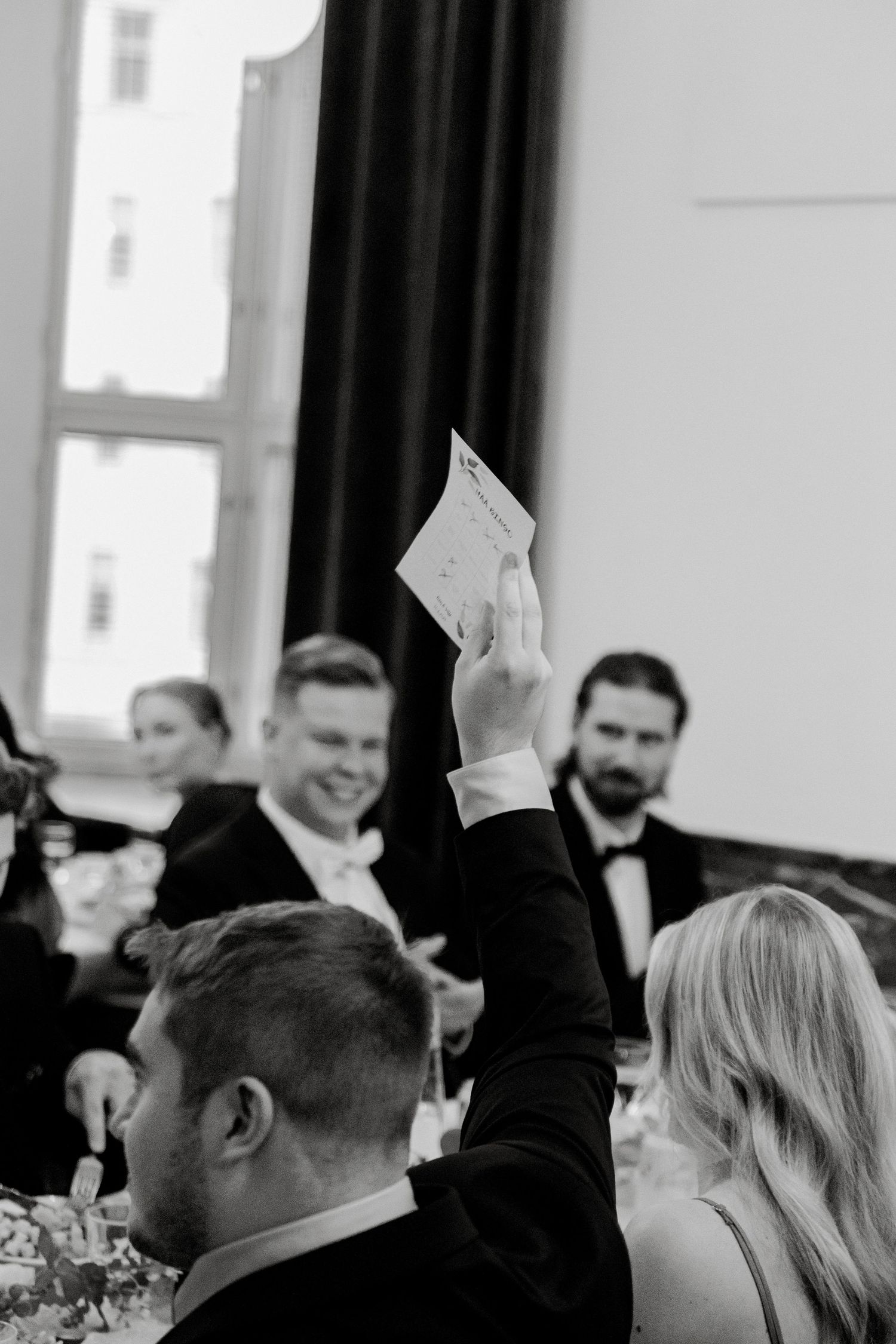 Wedding reception guests raising their hands in celebration during a festive moment.