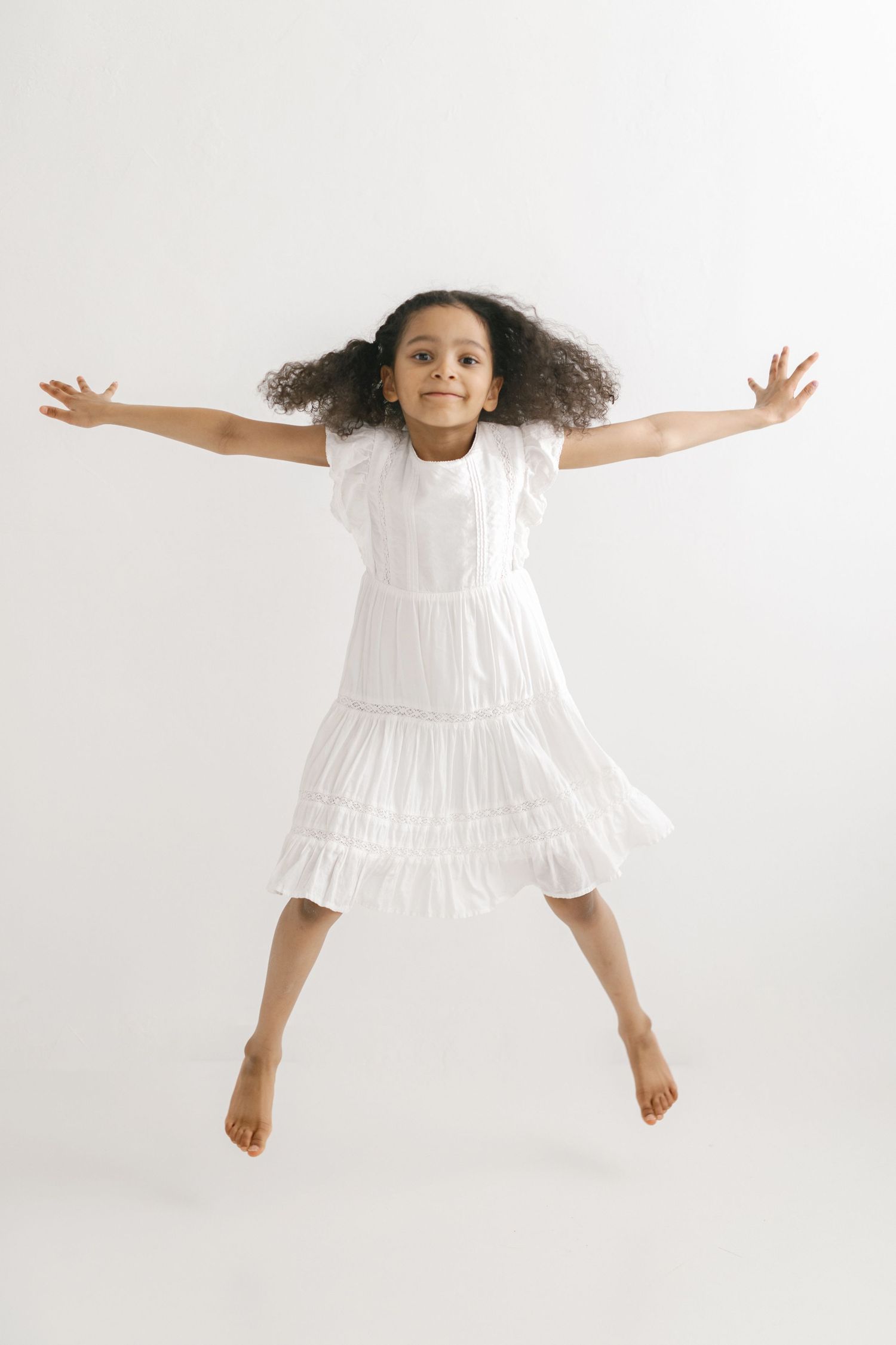 Jumping and dancing sequence in white dress against minimal background.