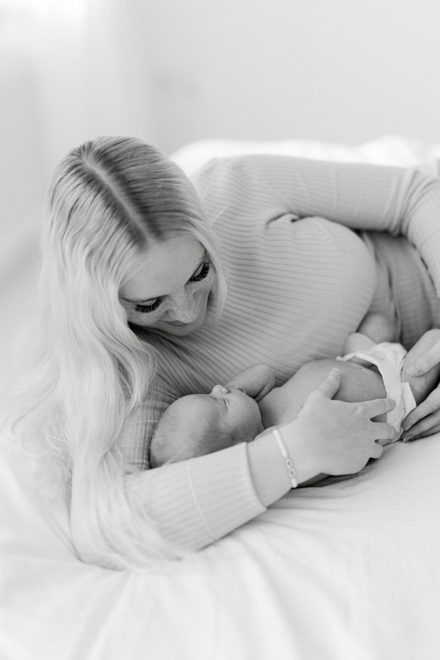 Black and white portrait of mother tenderly embracing sleeping newborn.