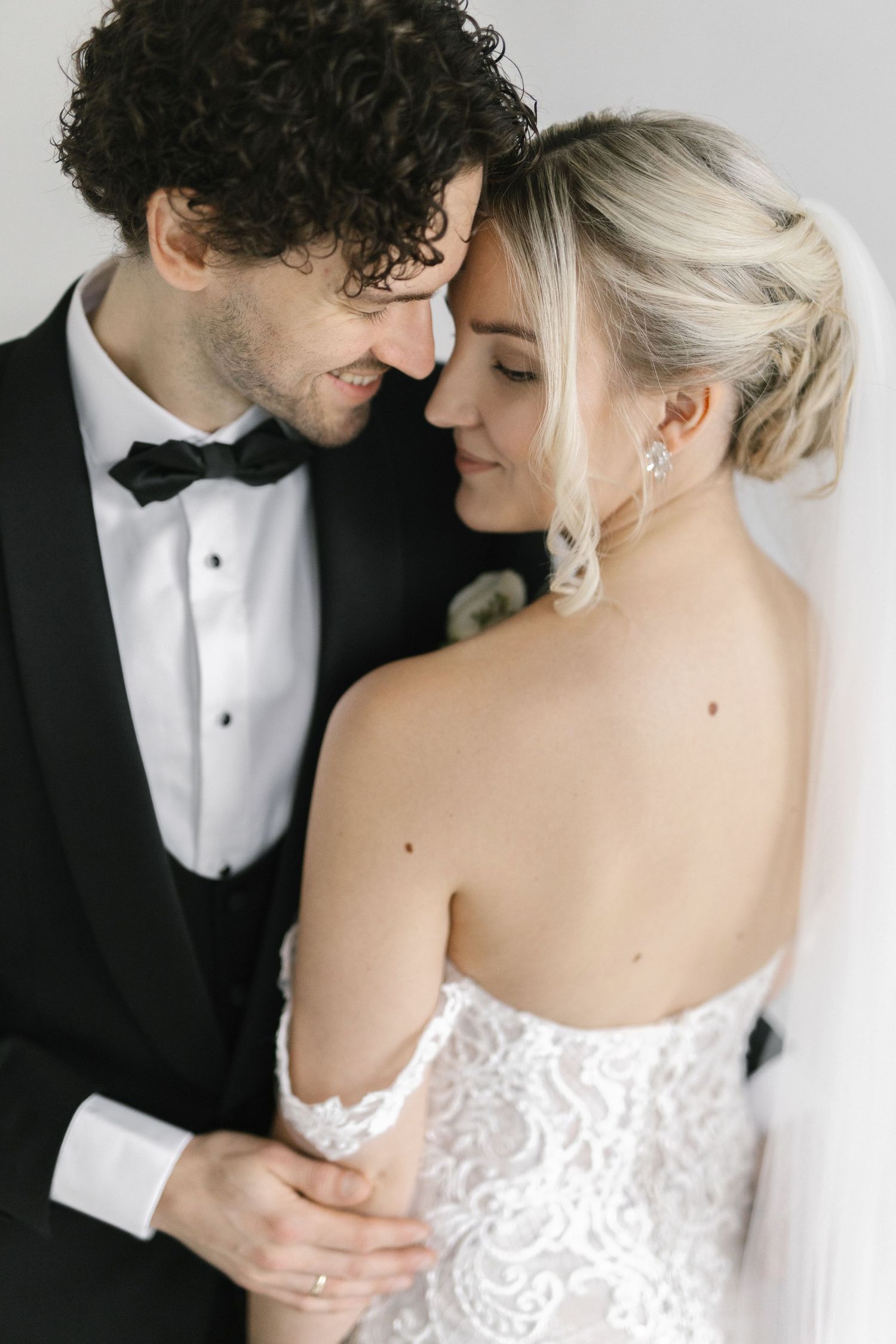 Intimate wedding portrait showing tender moment between newlyweds in formal attire.