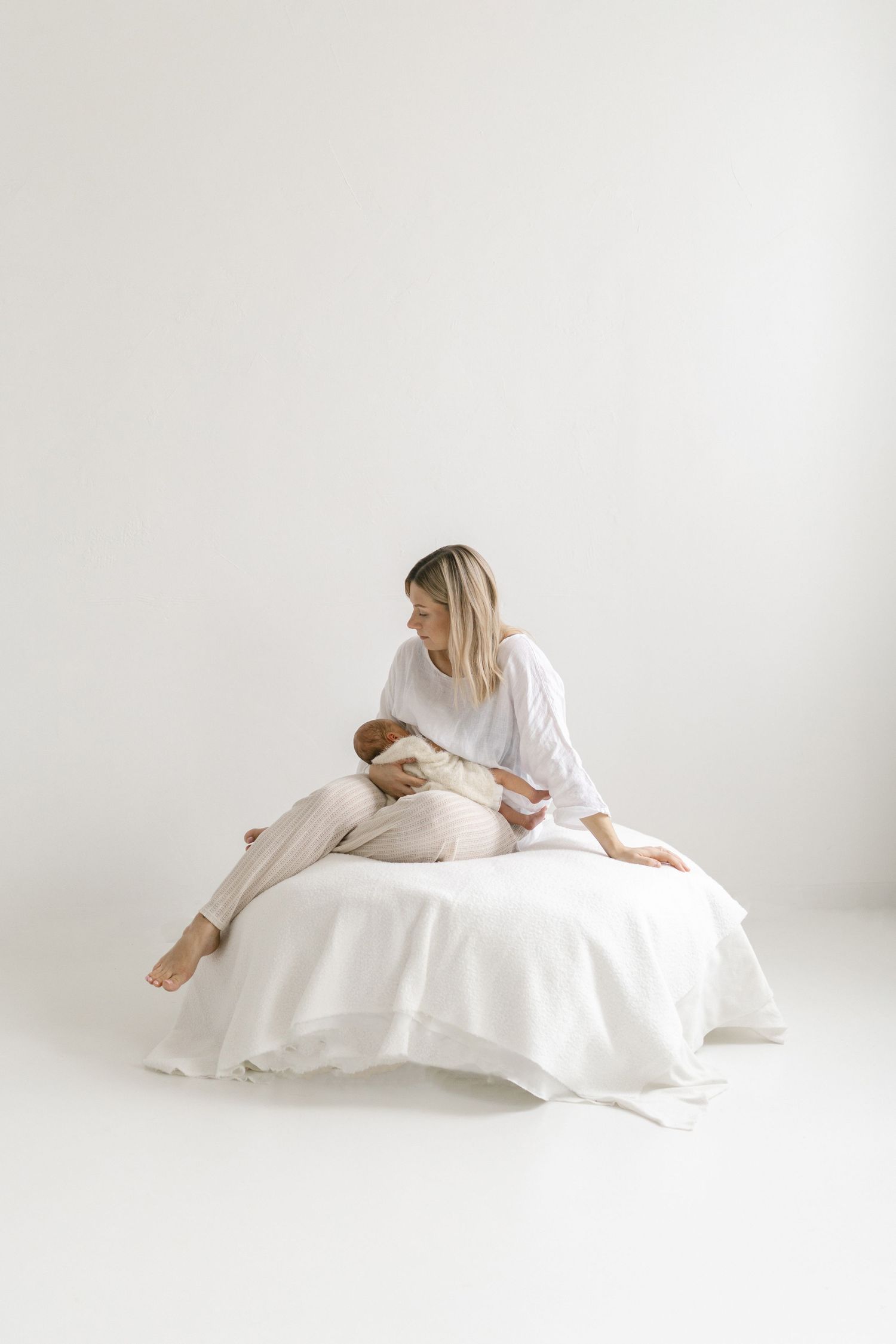 Minimalist white studio photos of a person in flowing fabric creating ethereal maternity poses.