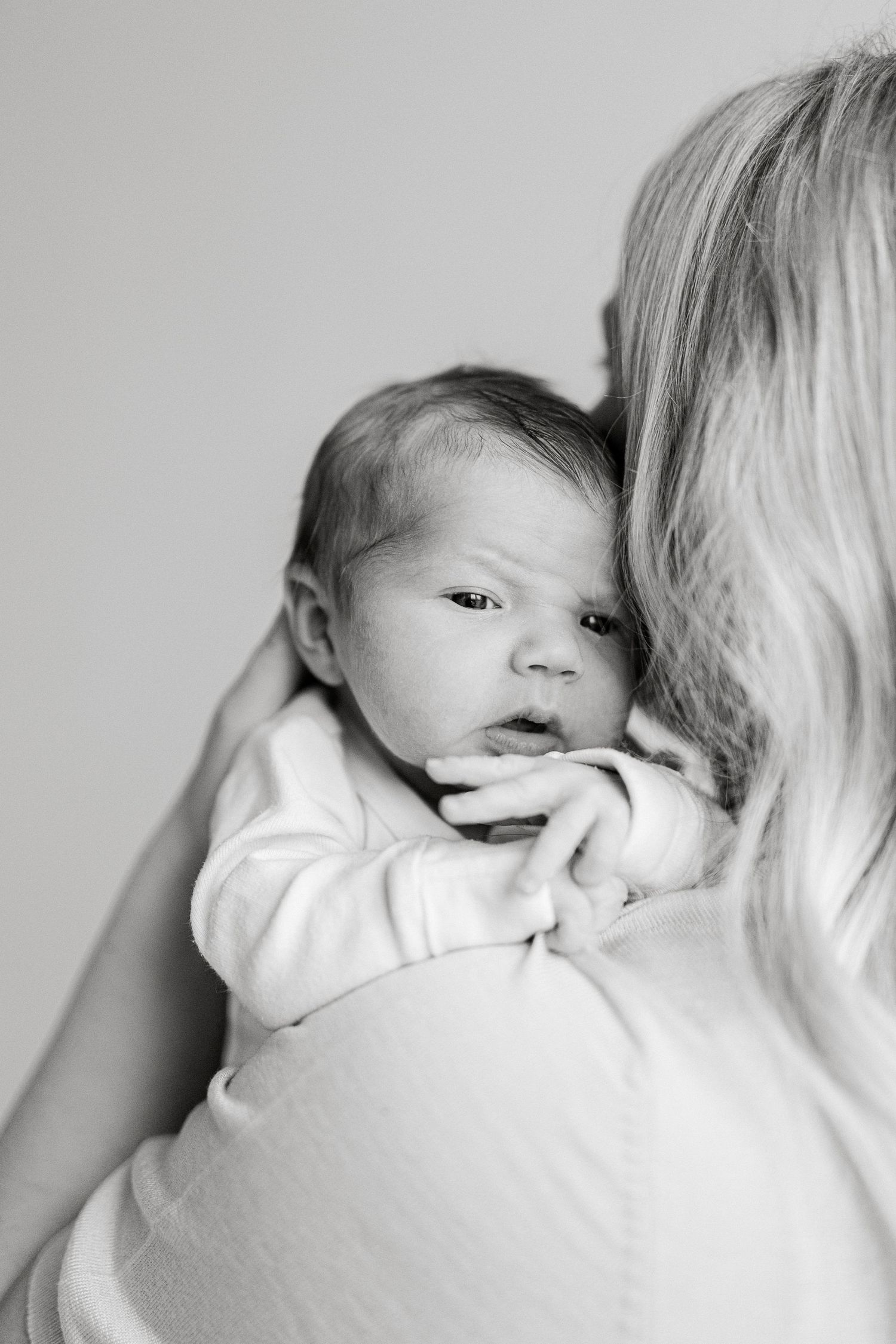 Series of tender moments between parent and newborn in black and white.