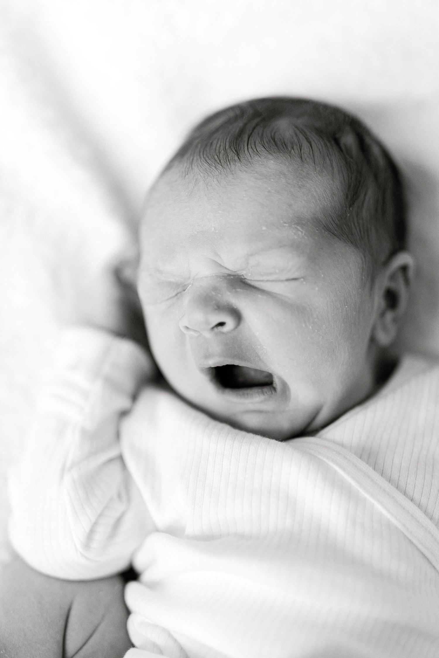 Black and white portraits of sleeping newborn in soft lighting.