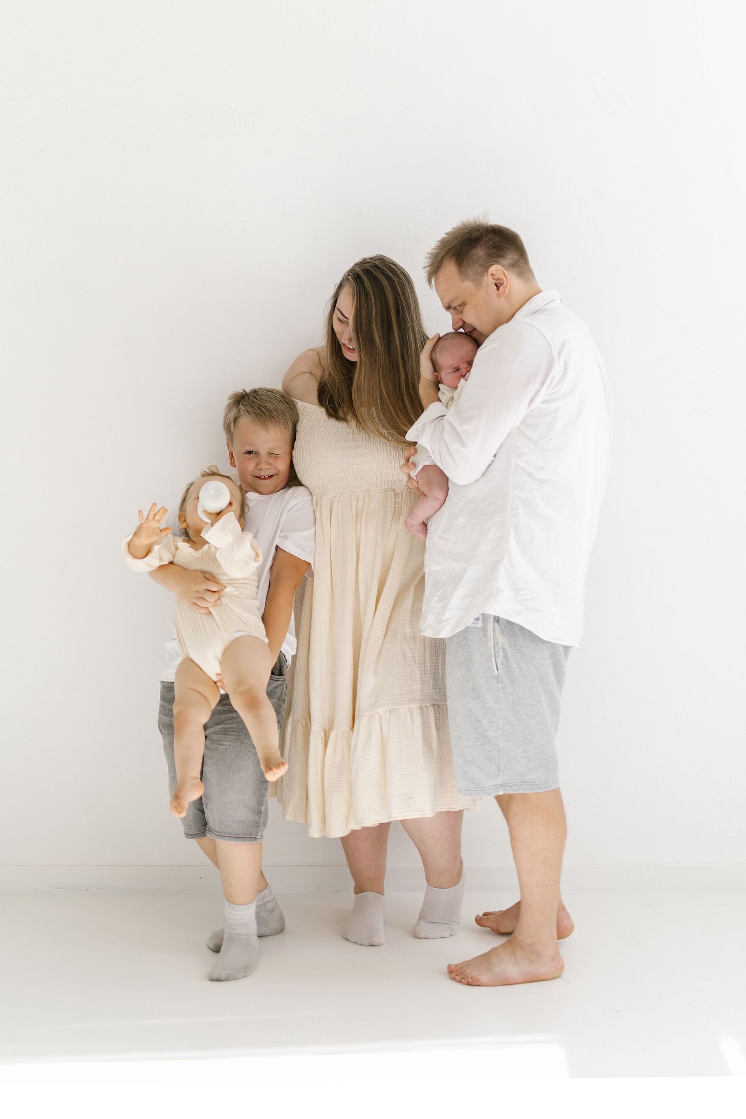 Family portrait against white background with children in light colored clothing.