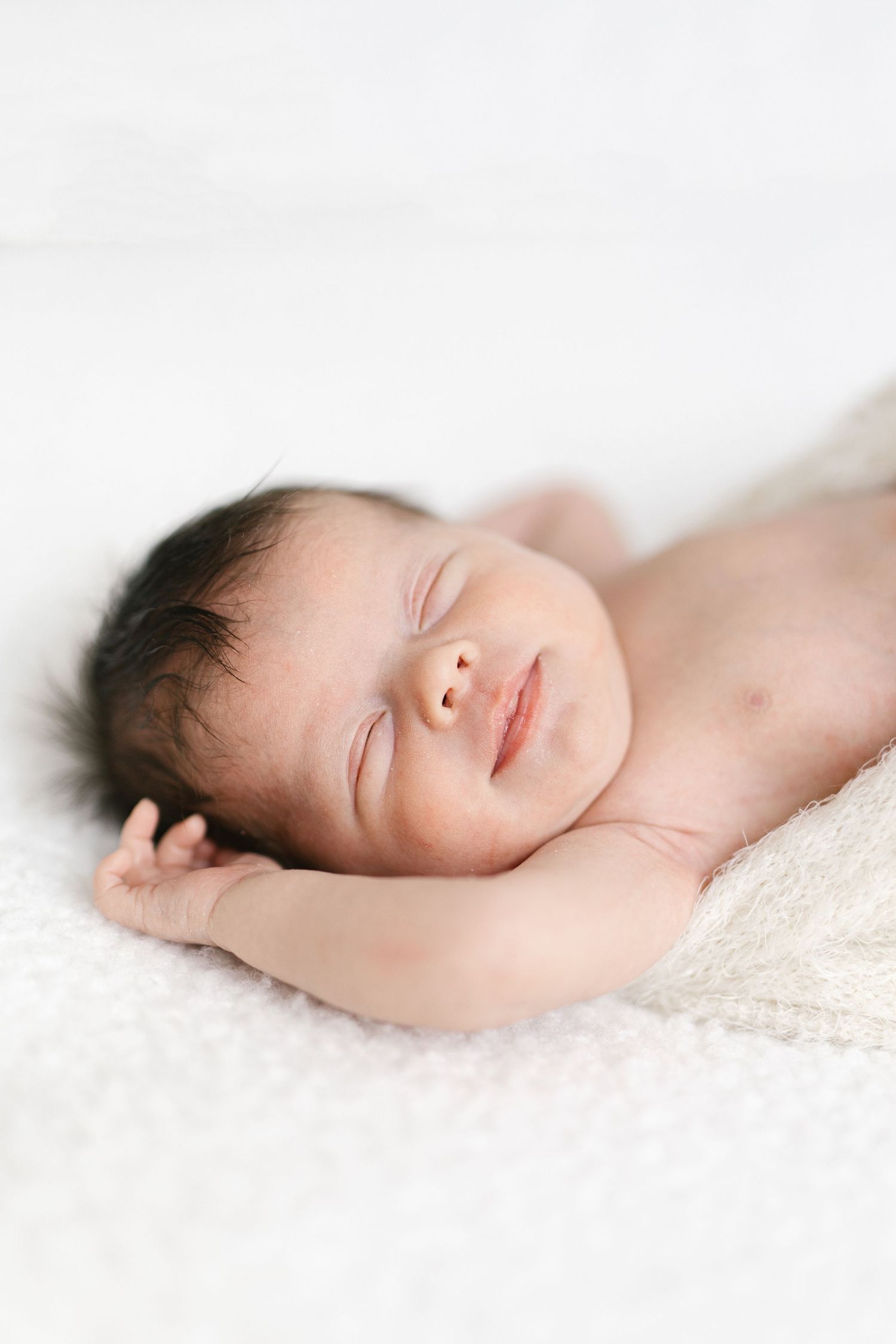 Peaceful newborn baby sleeping on soft white blanket in artistic black and white portrait.