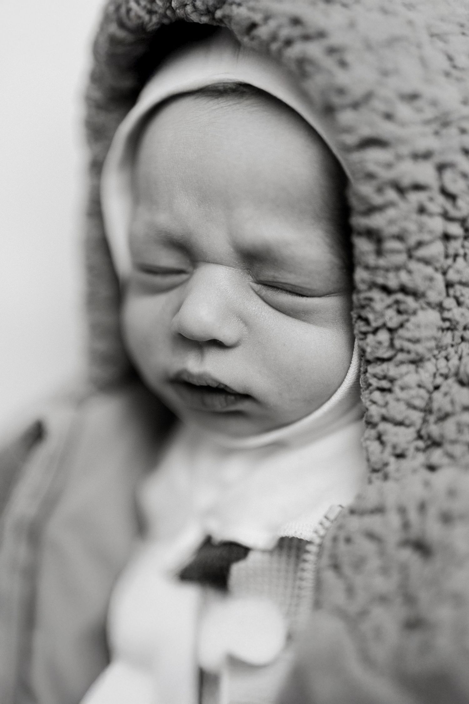 Black and white artistic close-ups of a peaceful sleeping newborn wearing white.