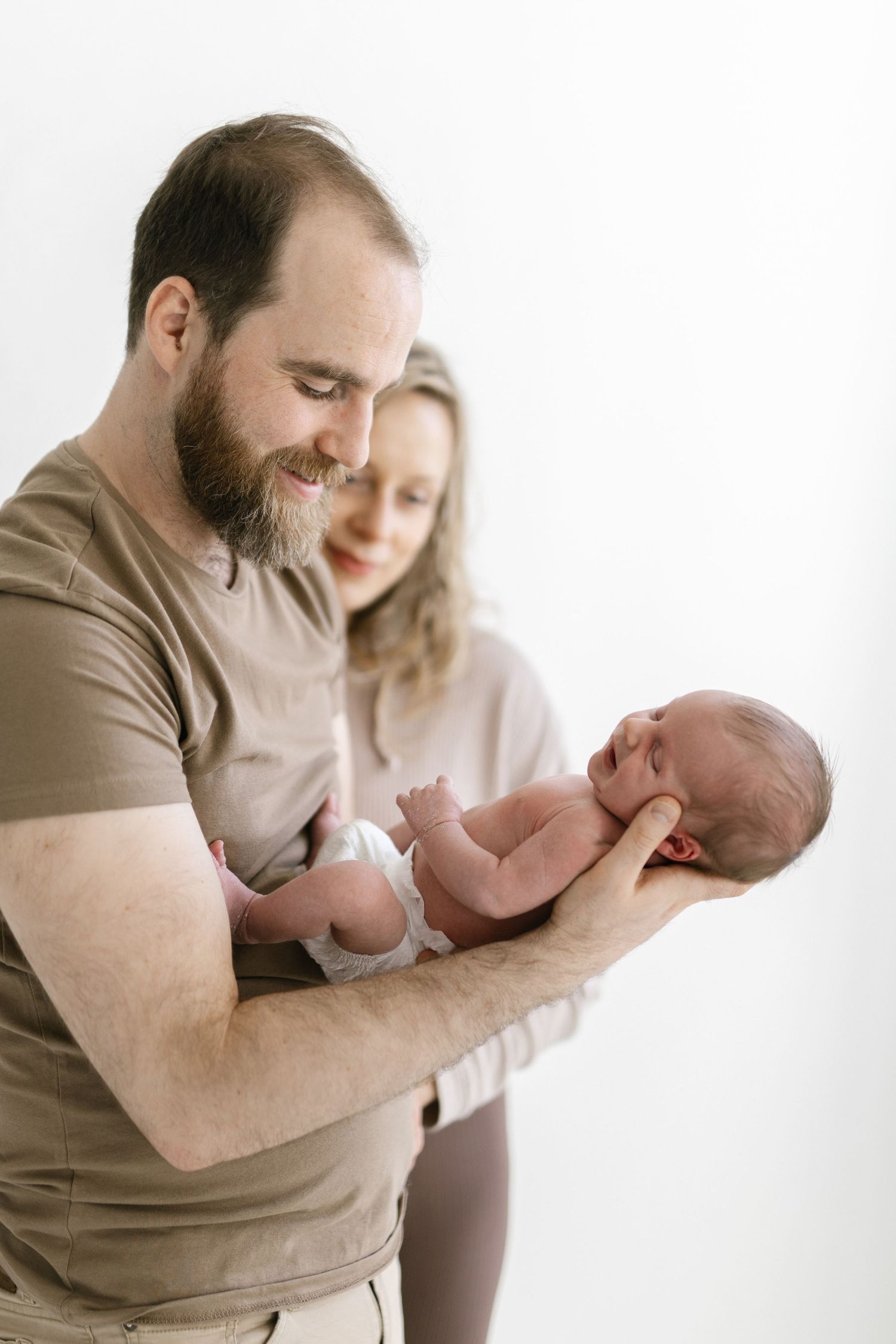 Tender moments between parents and newborn baby in soft natural light.