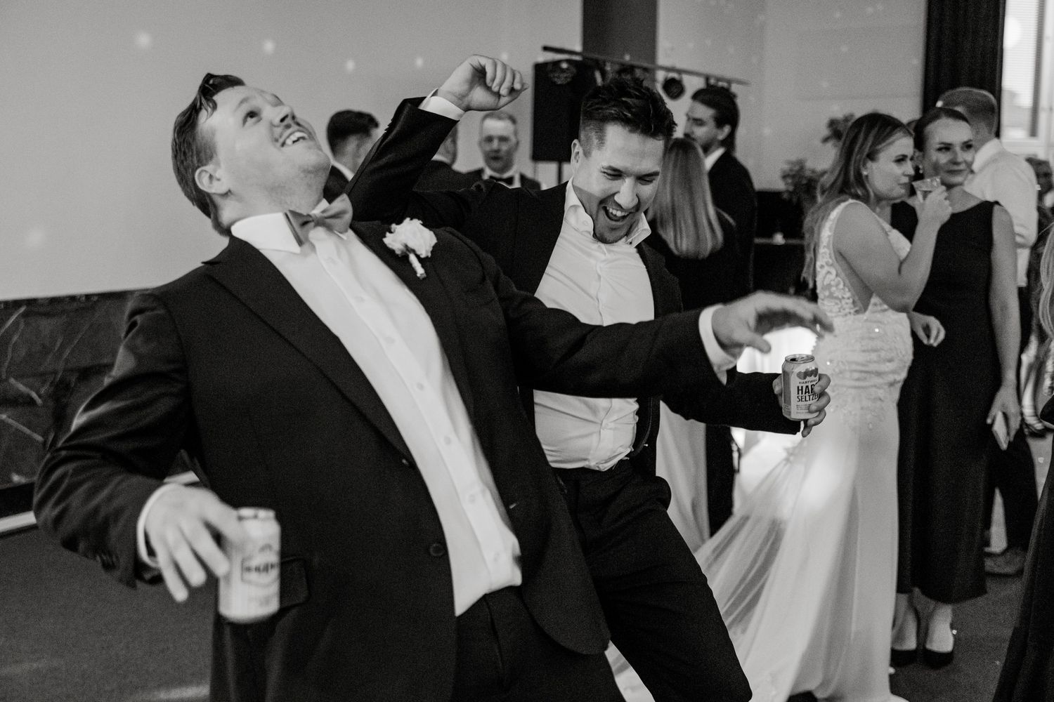 Black and white photo of wedding guests dancing and celebrating at the reception.