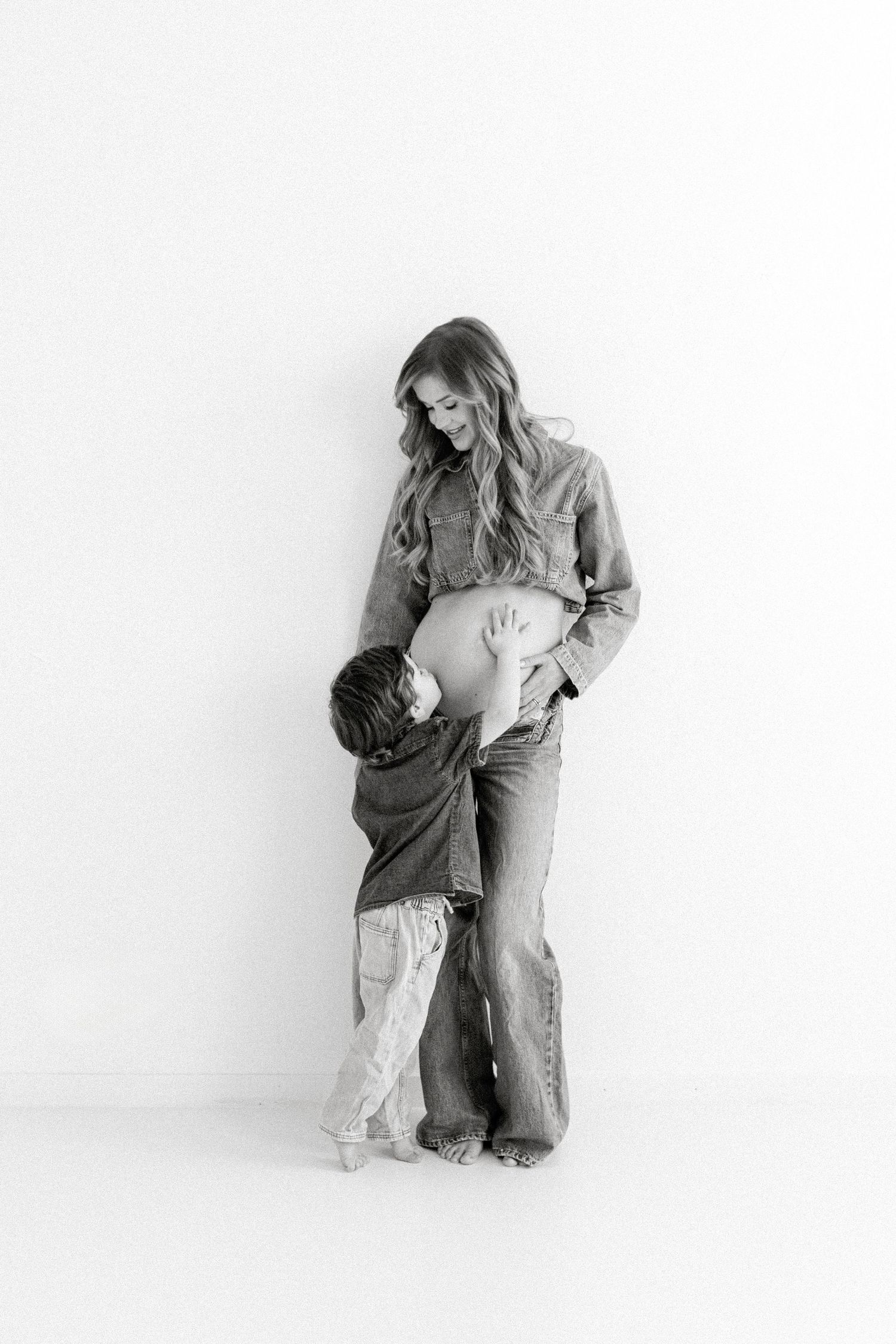 Black and white photo of mother and child sharing an intimate moment against white background.