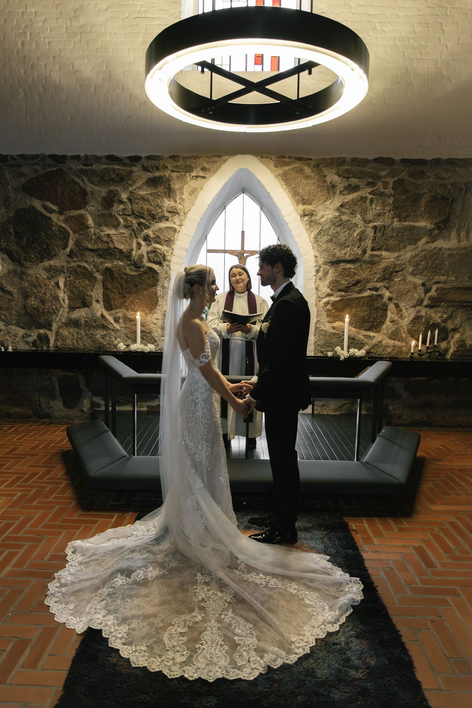 A romantic wedding ceremony in a rustic stone-walled room with dramatic lighting and a flowing white lace gown.