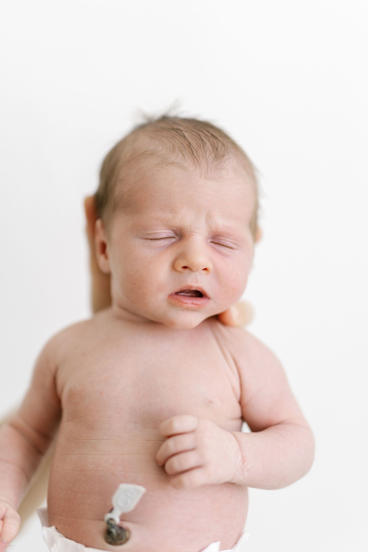 Series showing newborn baby with umbilical cord stump against white background.