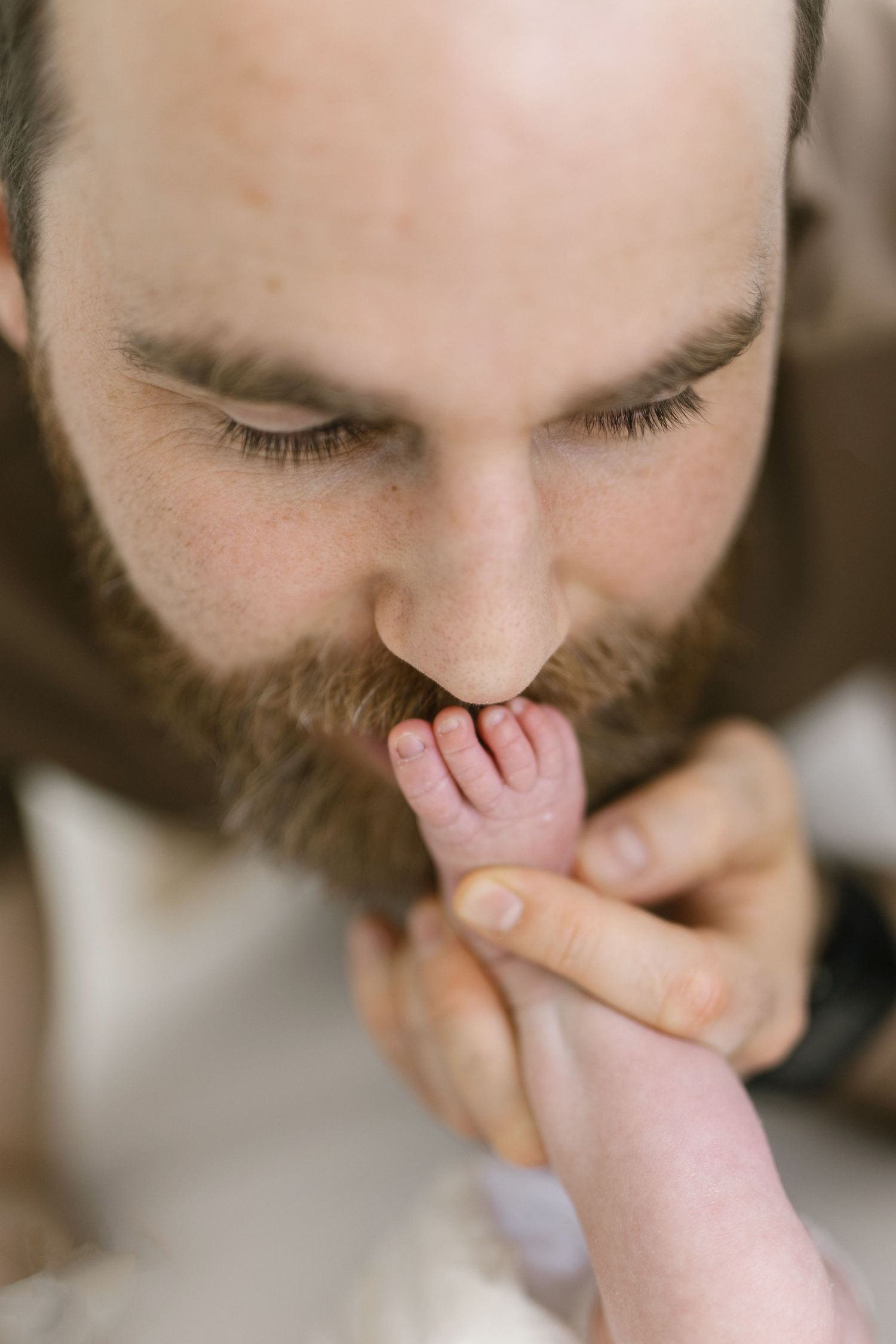 Close-up series showing parent kissing newborn baby's tiny feet.