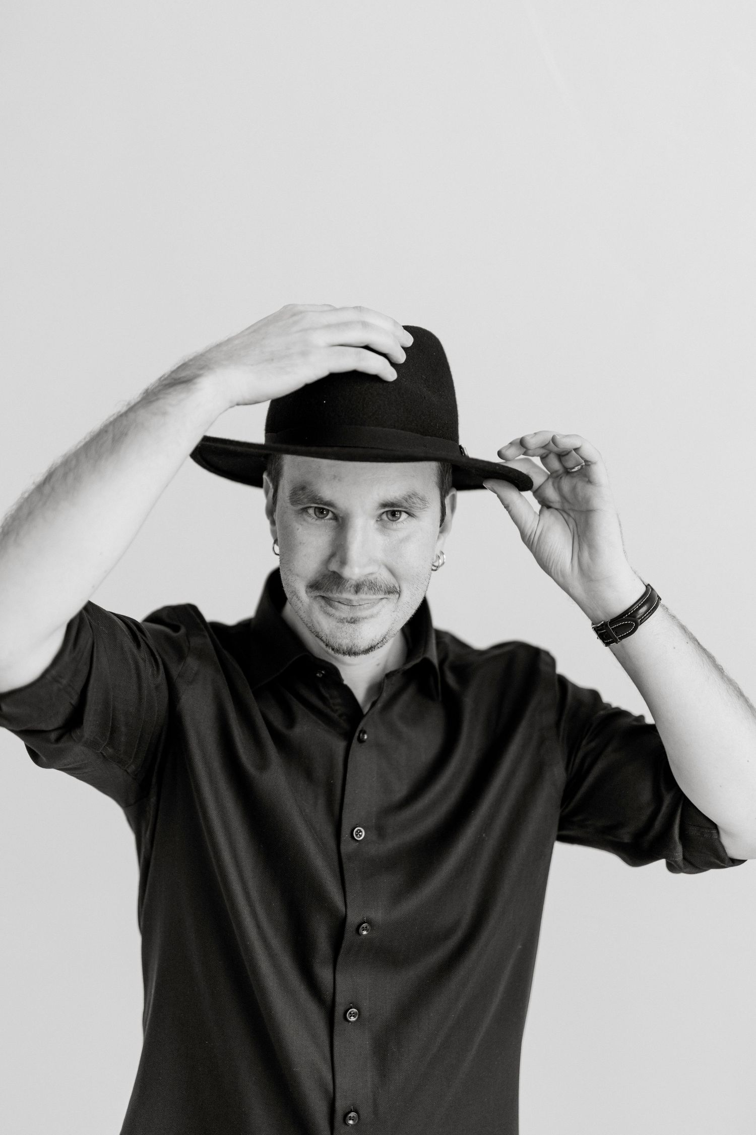 Black and white photo series showing someone in a dark shirt adjusting a baseball cap in multiple poses.