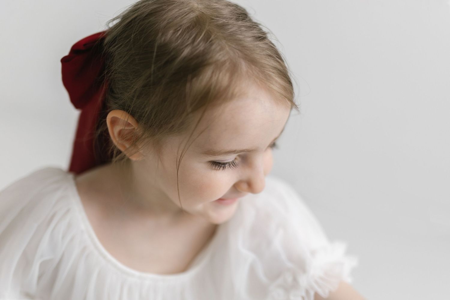 Artistic portrait series showing movement in white dress with red bow accent.