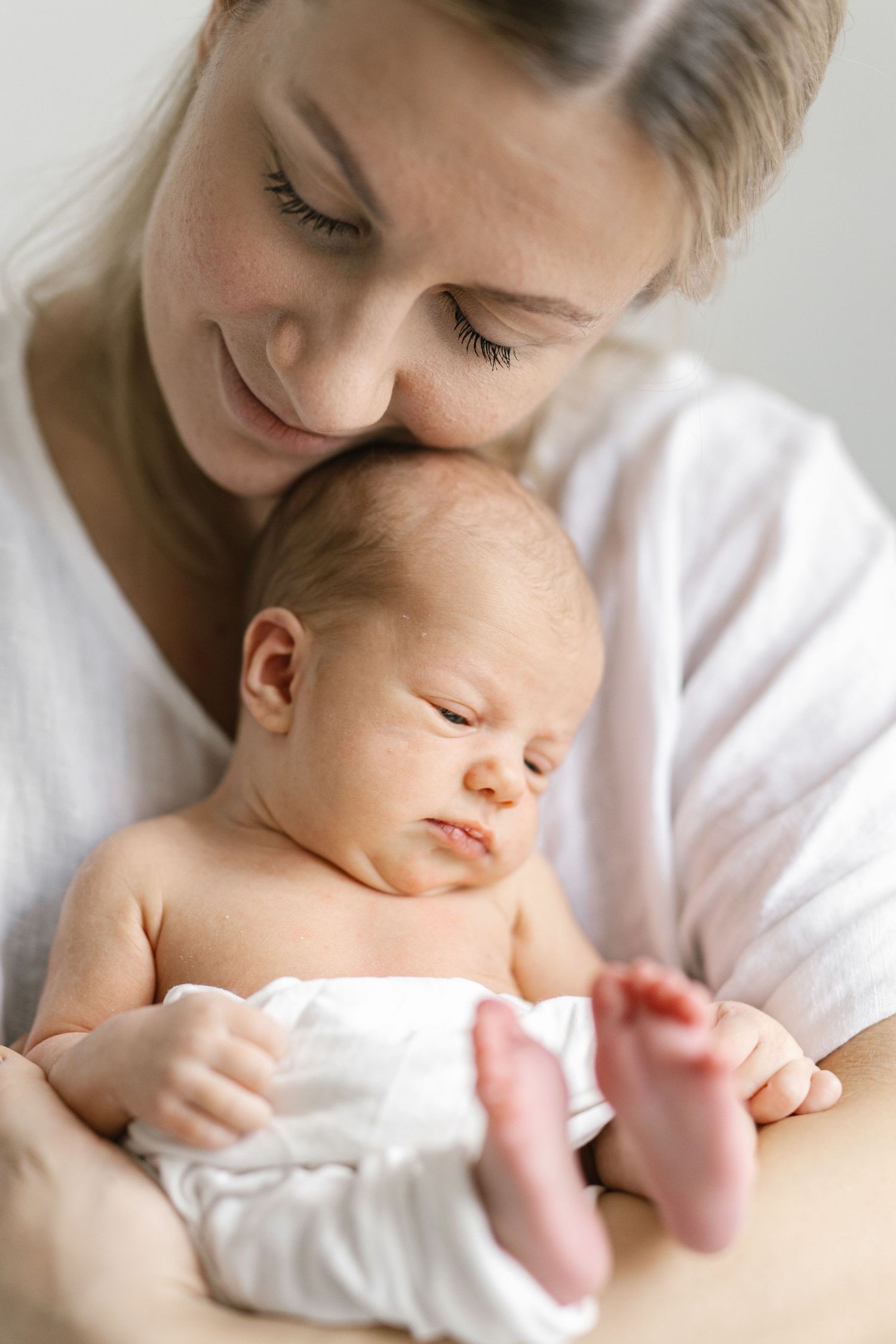 A series of intimate close-up shots showing tender moments between parent and newborn in soft lighting.