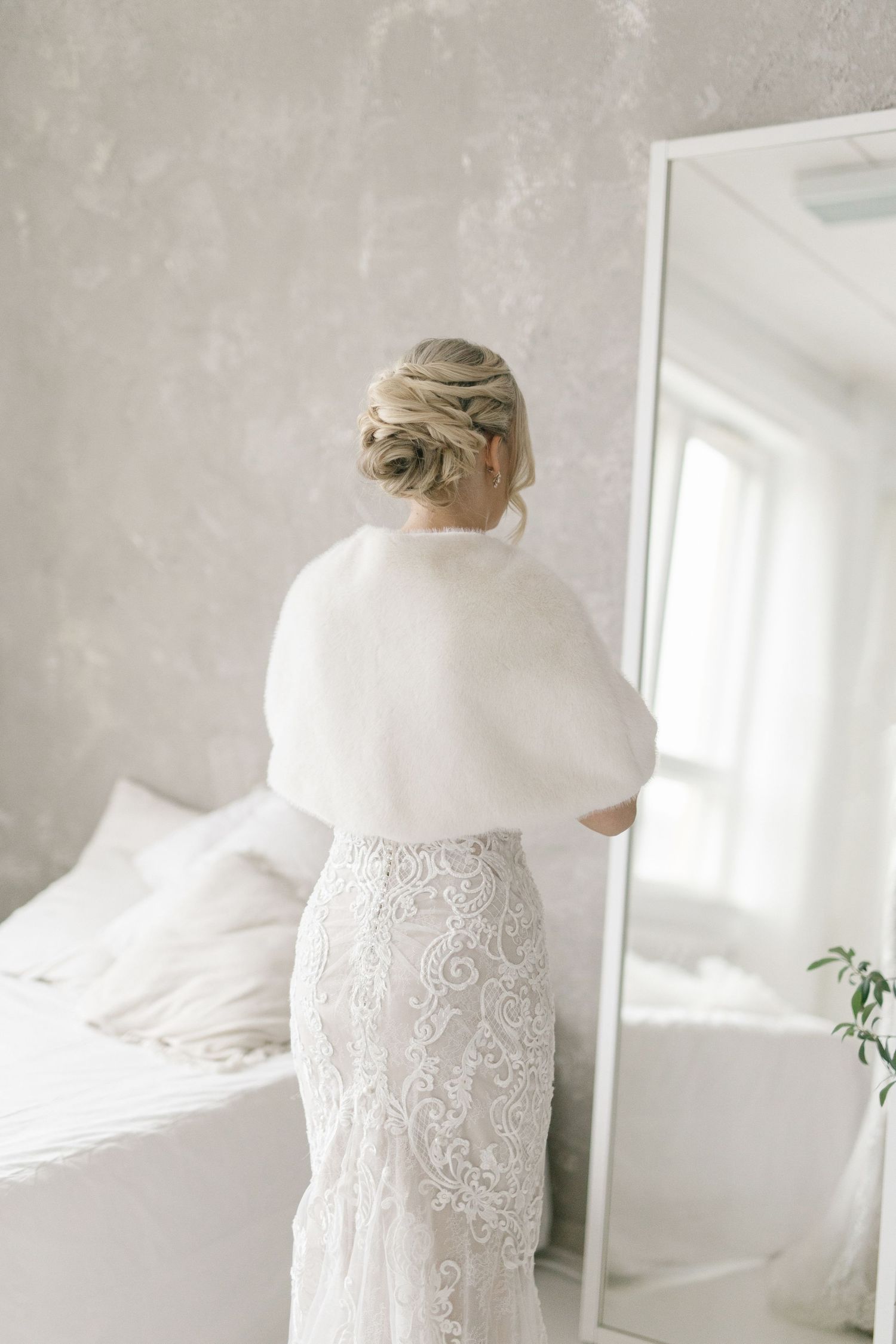 Bridal portrait session showing delicate details of white lace wedding gown against grey wall.
