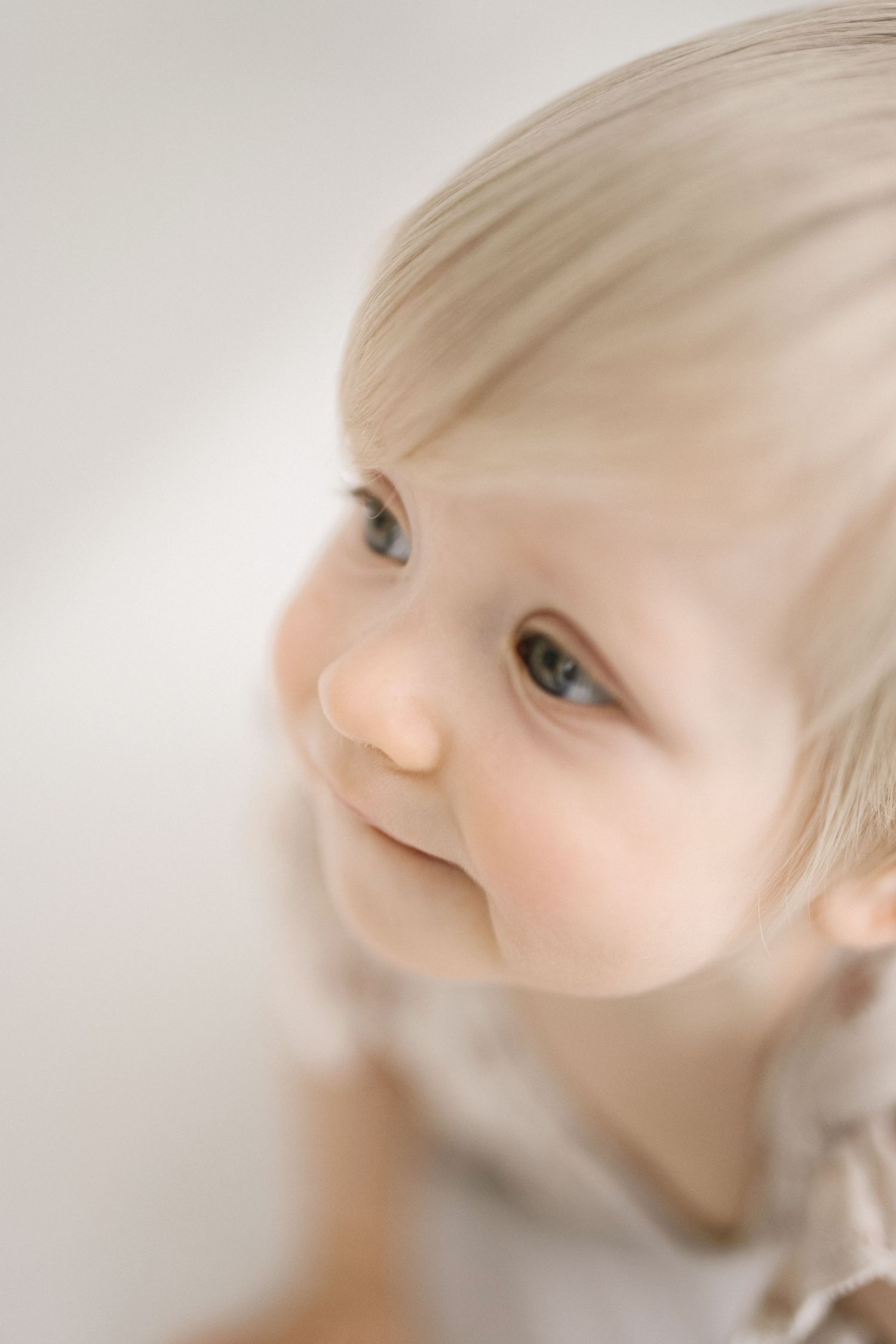 Close-up artistic portrait of a baby with soft focus and ethereal lighting against white background.