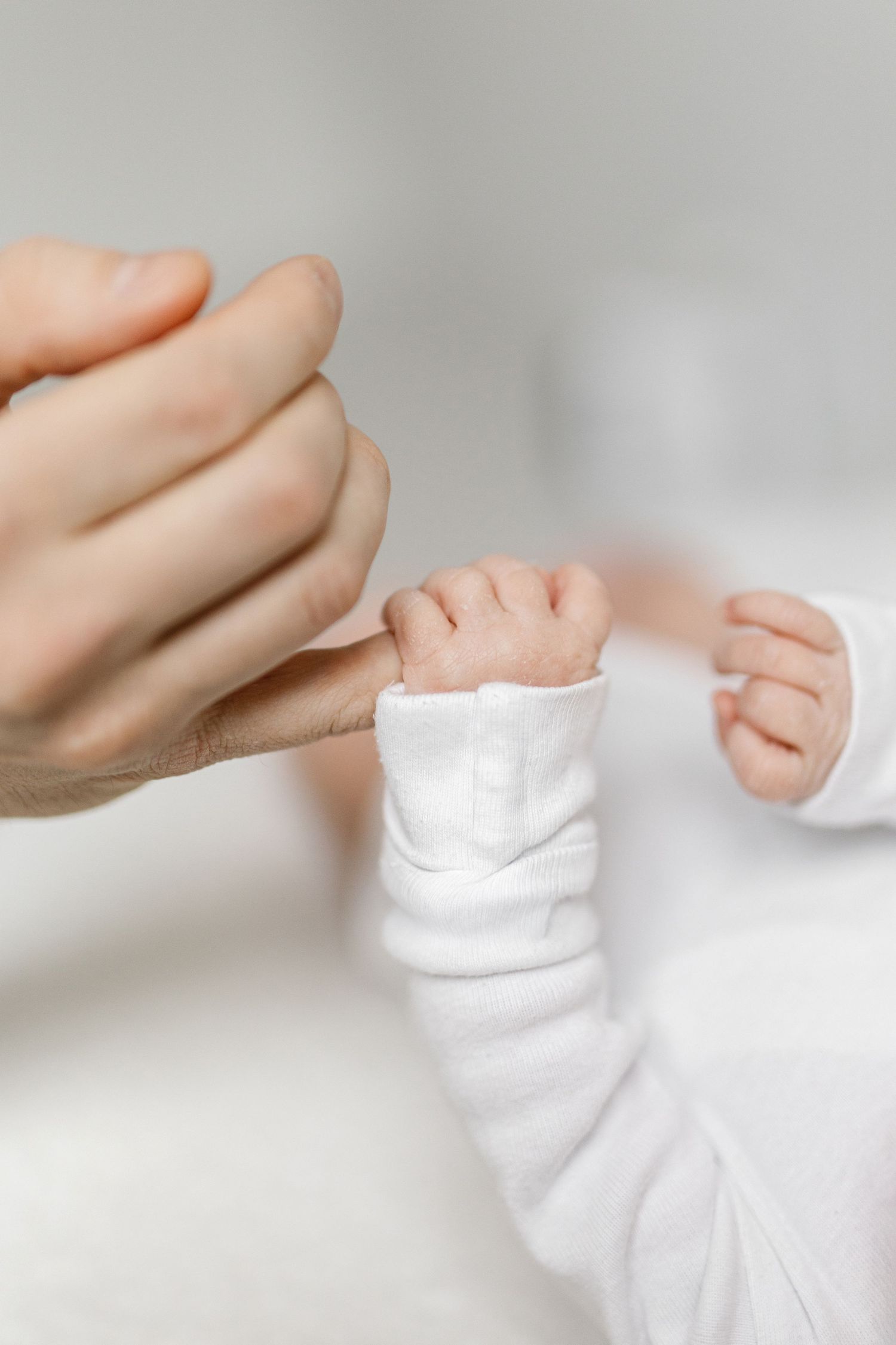 Close-up of tiny baby feet in white onesie.