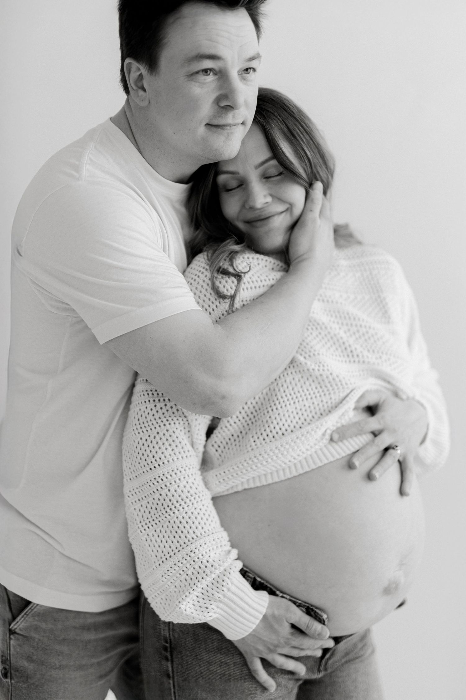 A series of black and white intimate maternity photos showing a couple embracing and cradling a pregnant belly.