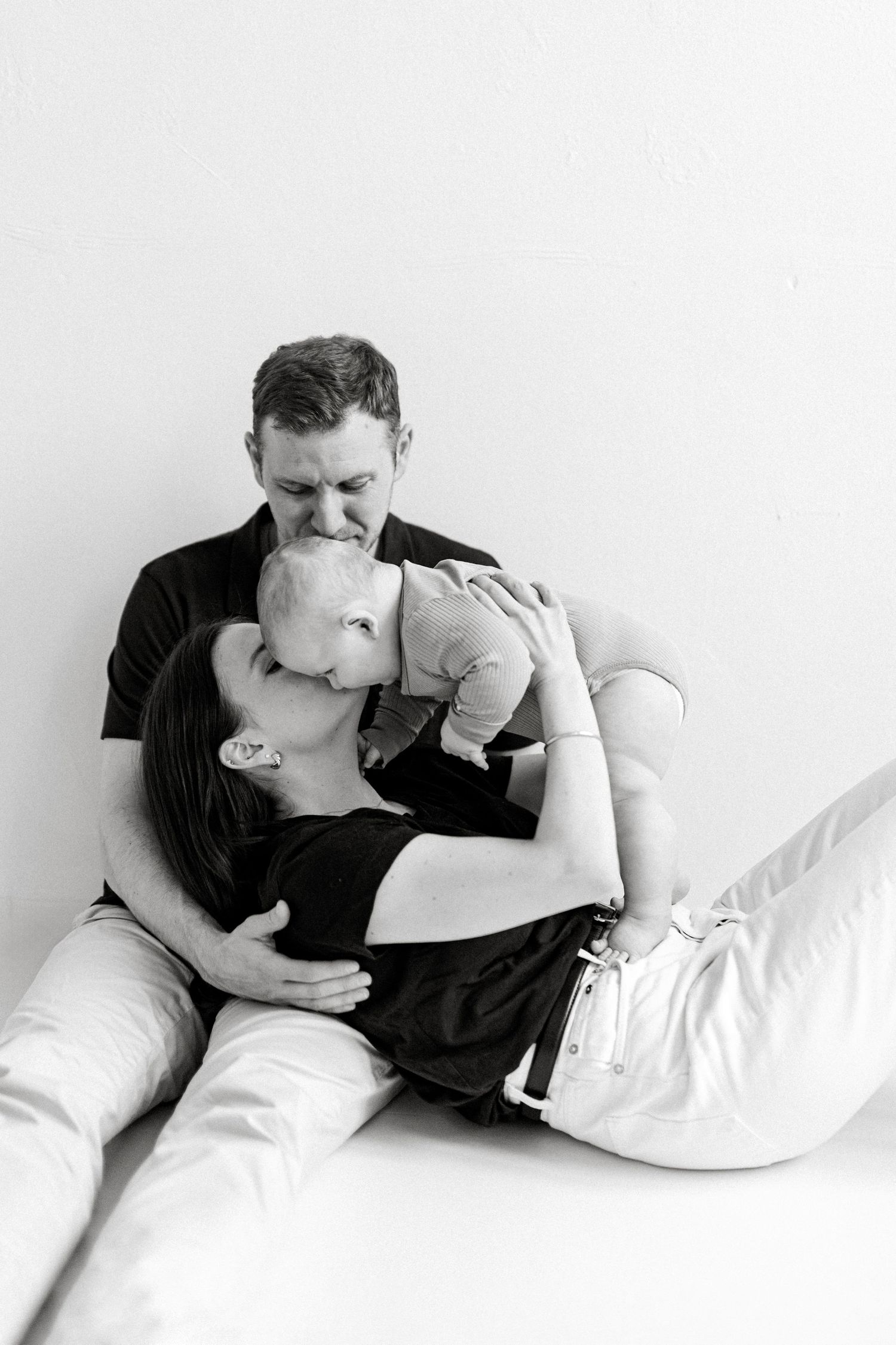 Black and white portrait of family bonding moment on white background.