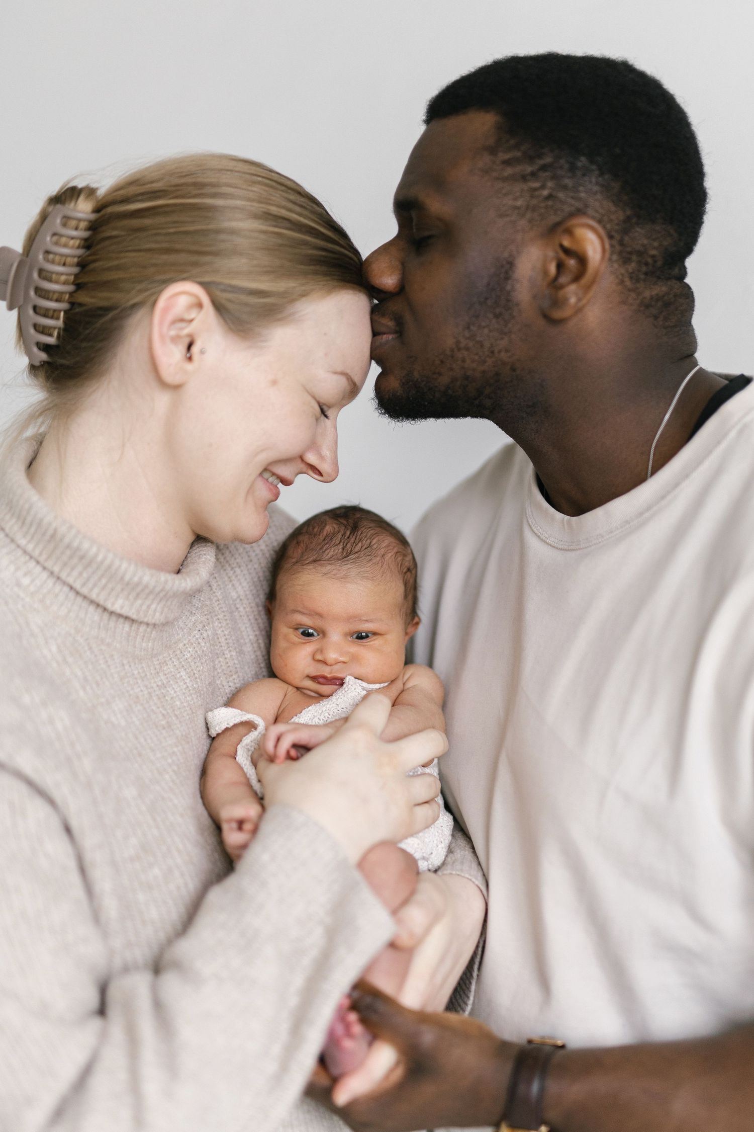 Intimate family moment as parents embrace their newborn baby with tender affection.