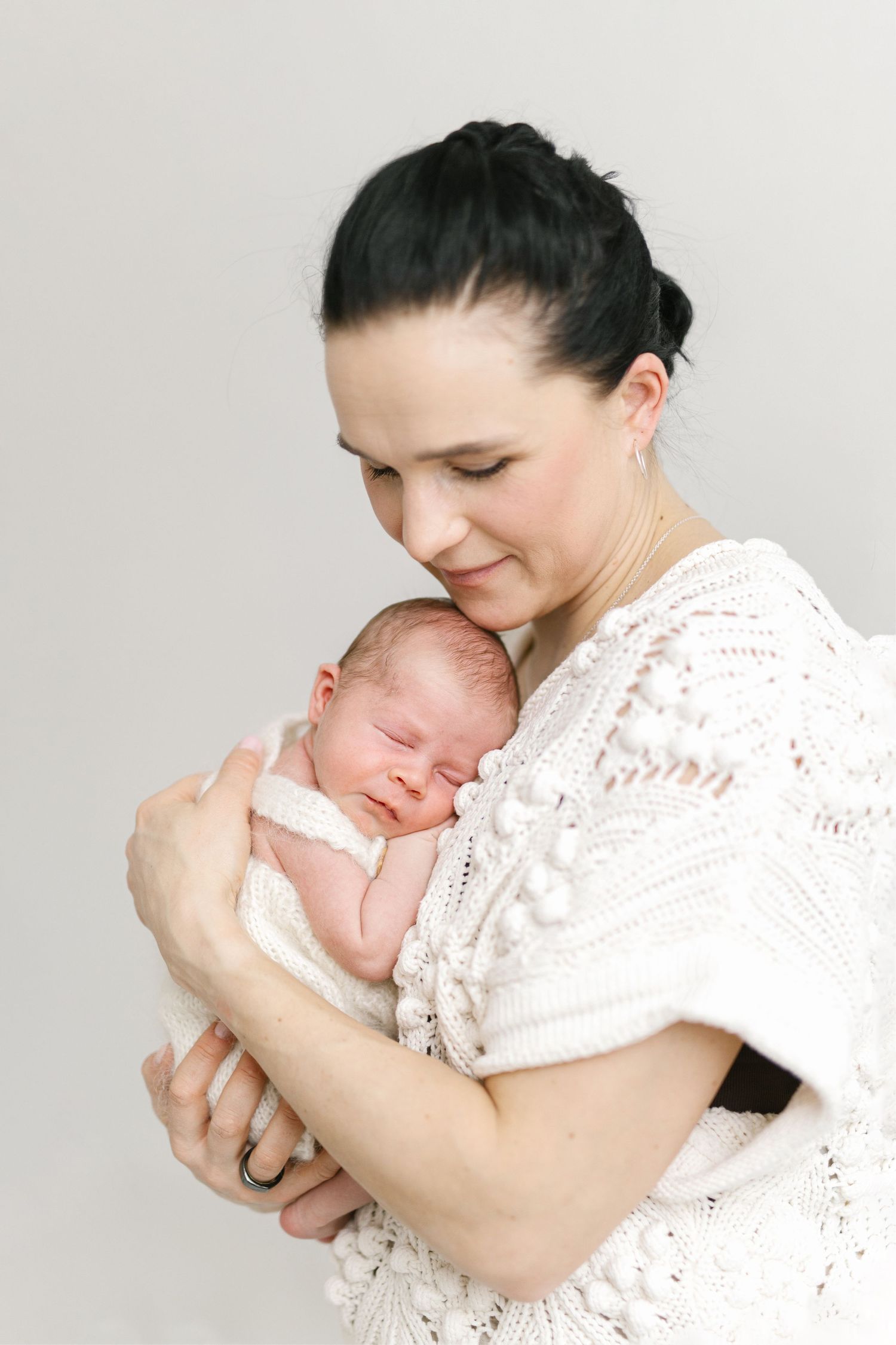 Intimate portrait series of tender moments with a newborn baby in white lace.