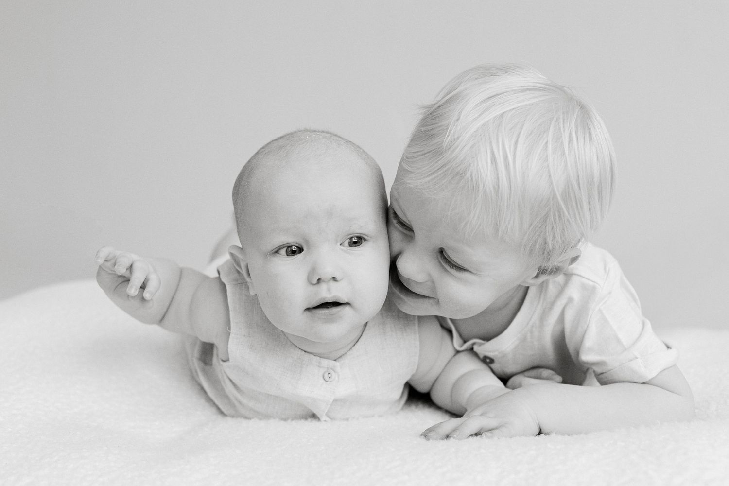 Black and white portrait of two young siblings lying close together.