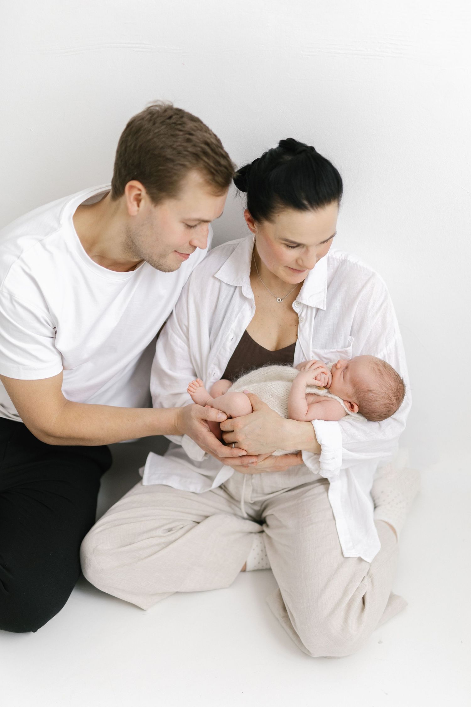 Family photo series on white background showing intimate moments with their newborn.
