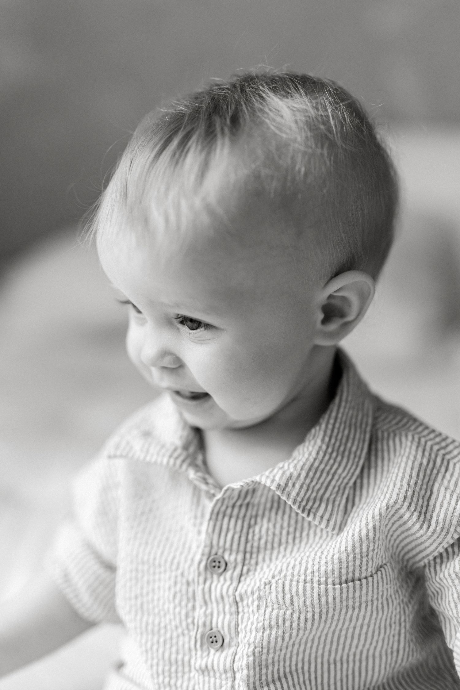 Black and white portrait of a smiling baby in a striped shirt, looking to the side.