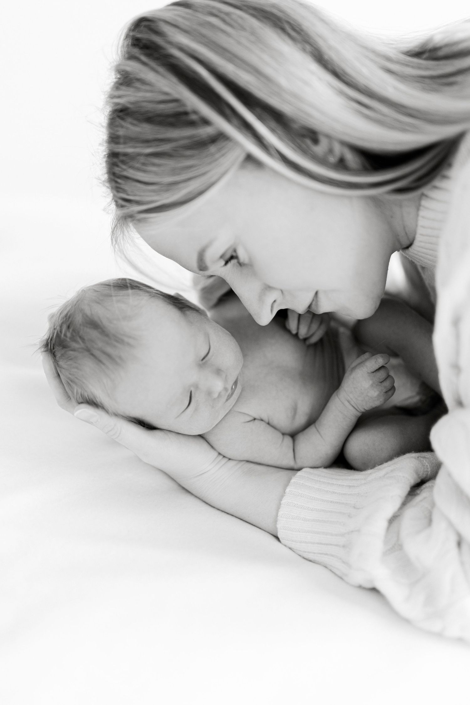 Black and white intimate portrait of tender moment between parent and newborn.