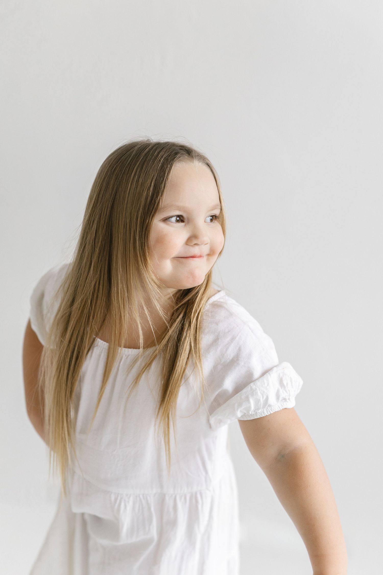Series of playful poses in a white dress against light background showing joyful movement and expression.