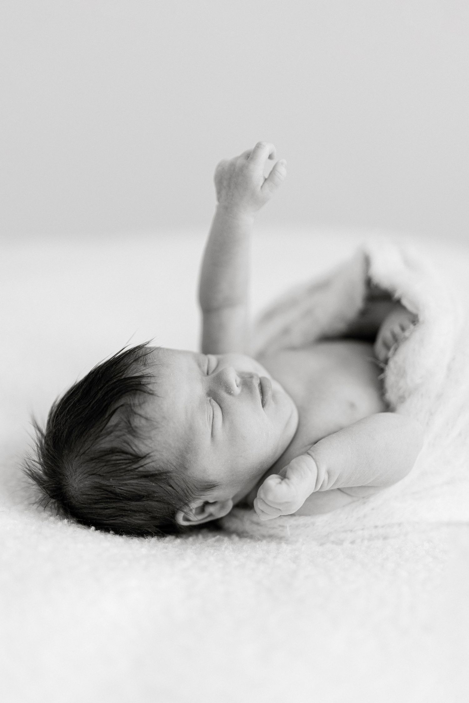 Serene sleeping newborn resting on white textured surface in minimalist style.