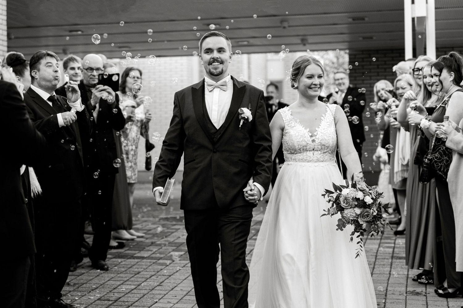 Newlywed couple exits ceremony while guests throw confetti in celebration.