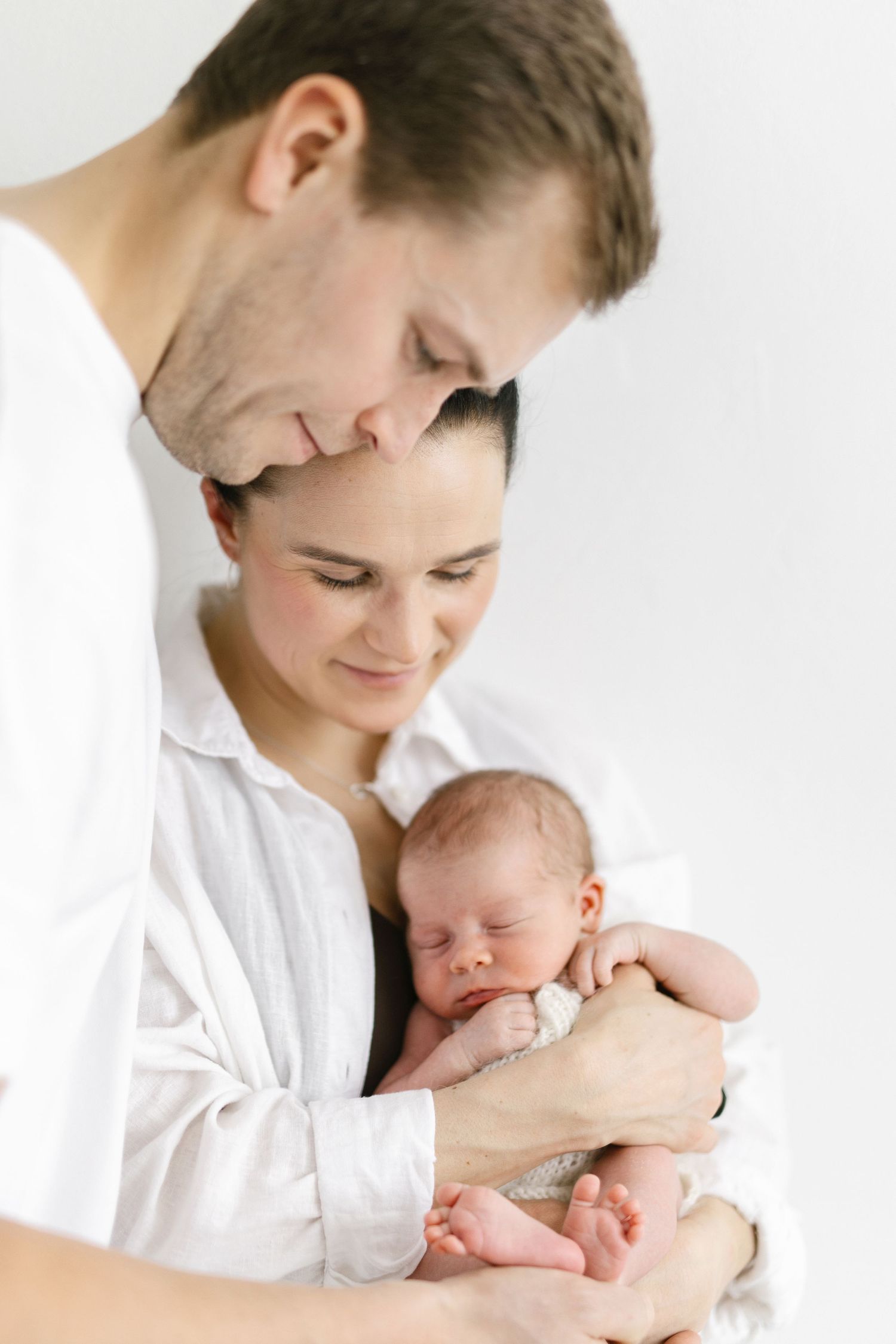 Minimalist studio portraits showing tender moments with a sleeping newborn baby.