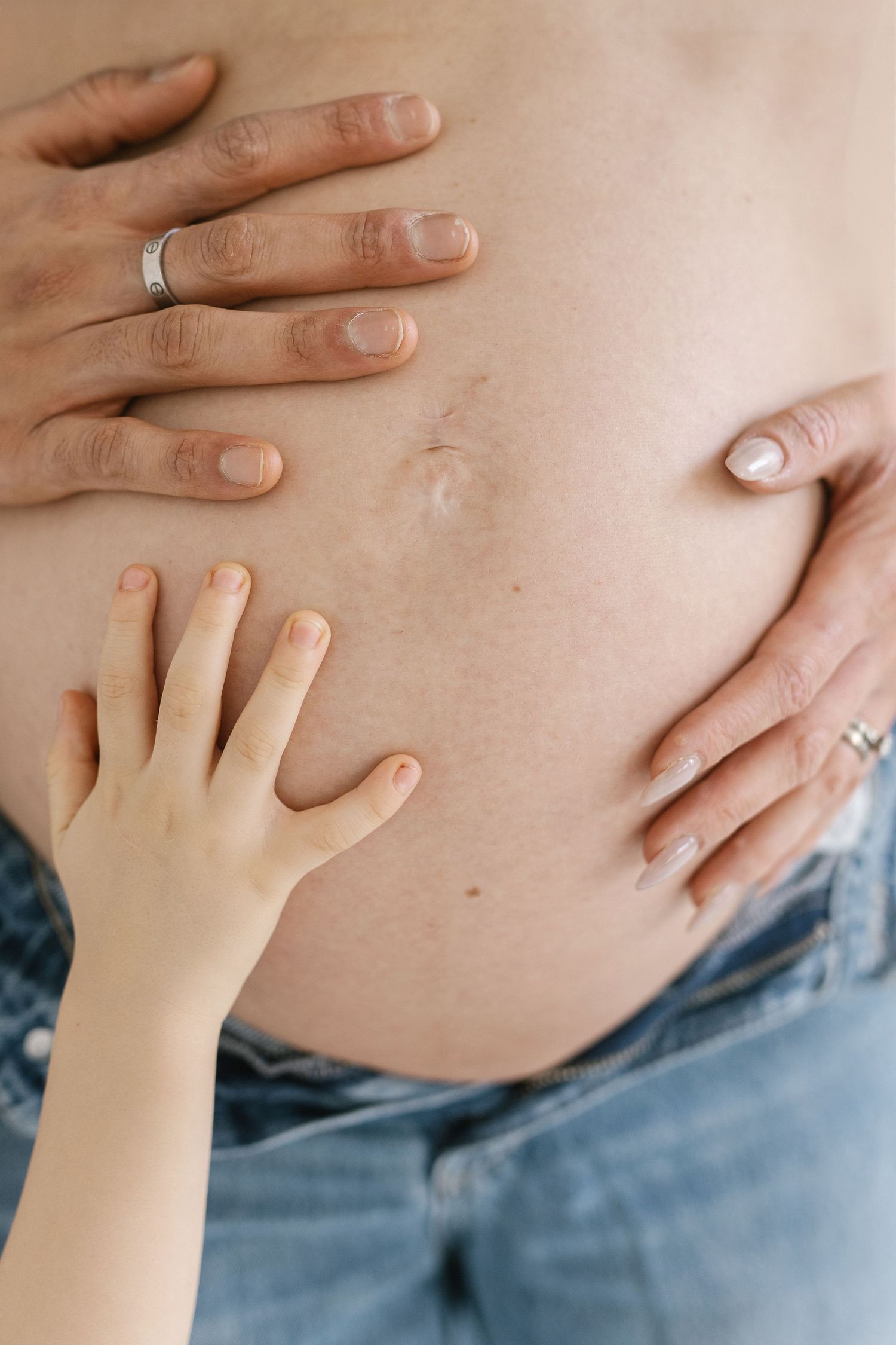 Close-up sequence of small child's hand touching a pregnant belly.