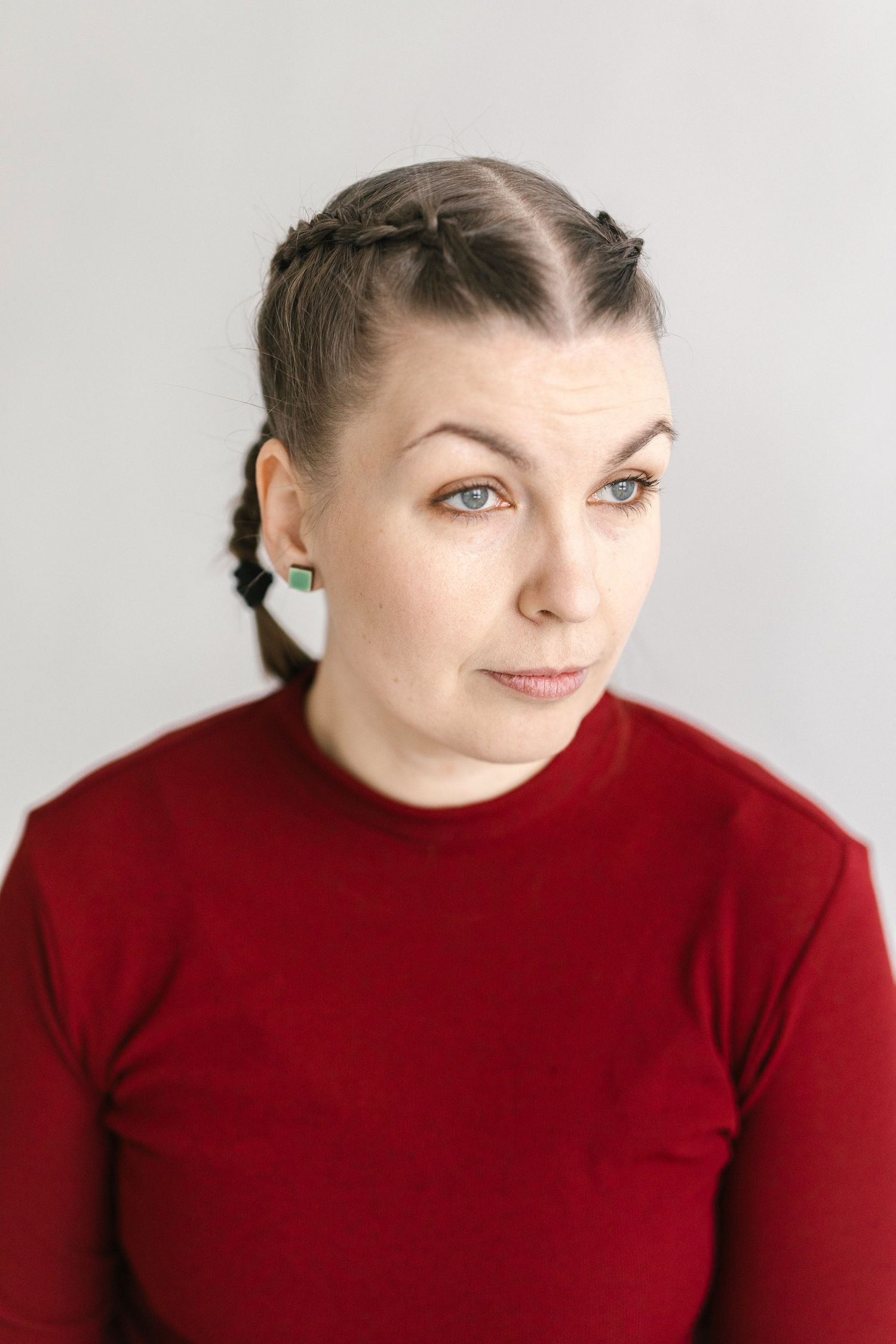 Person in red turtleneck making expressive faces against white background.