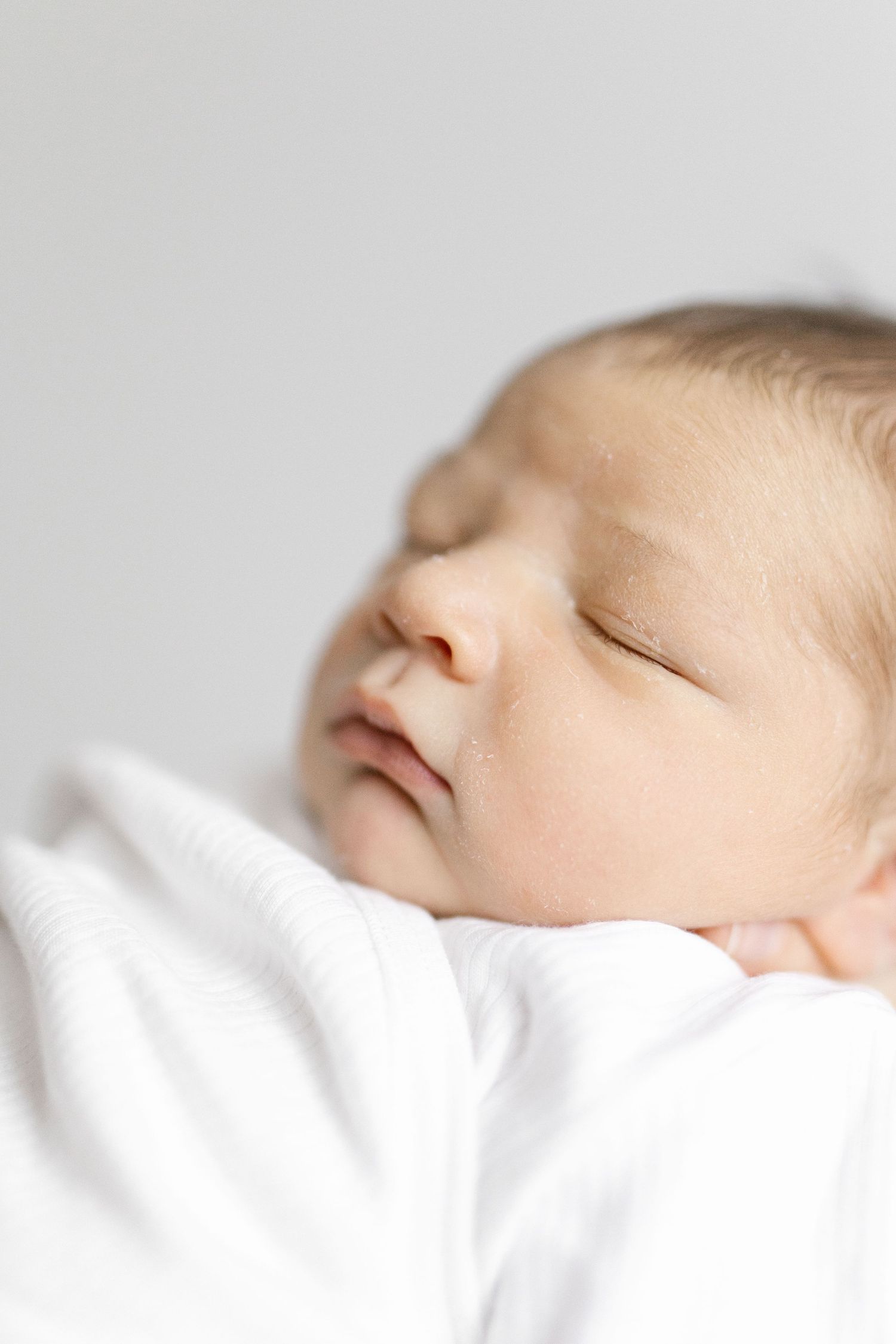 Close-up profile of sleeping baby's face against white bedding.