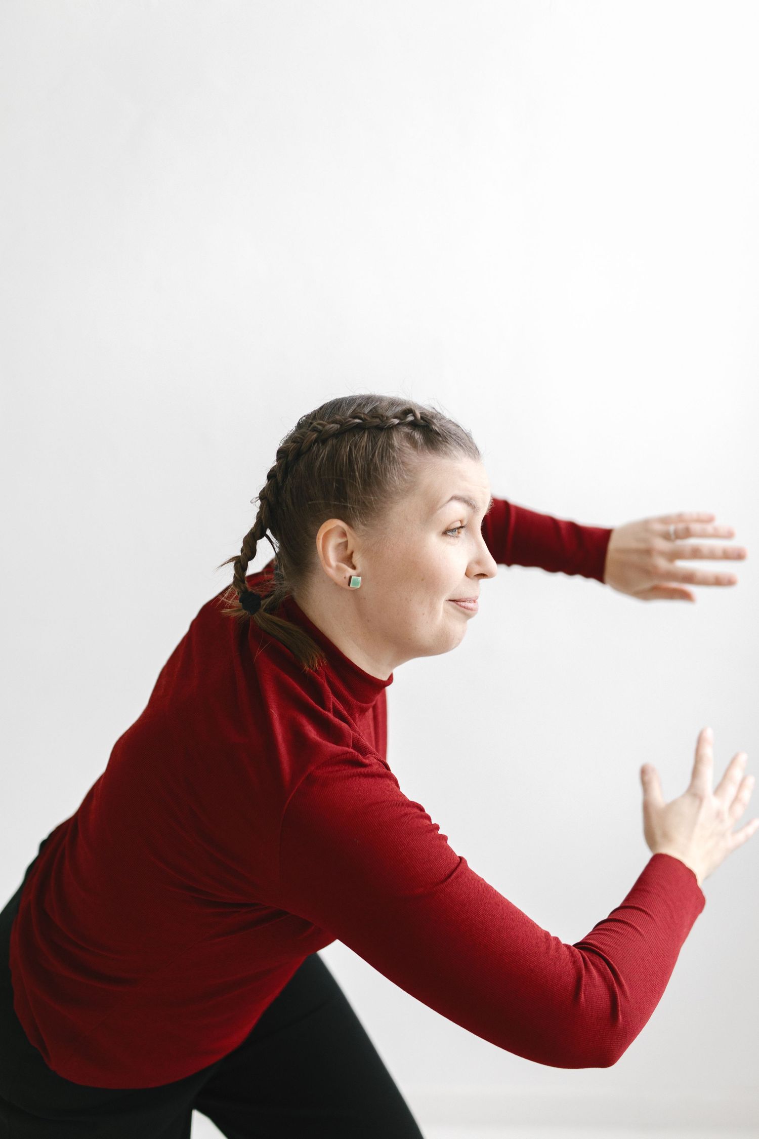 Person in red sweater making dramatic gestures against white backdrop.