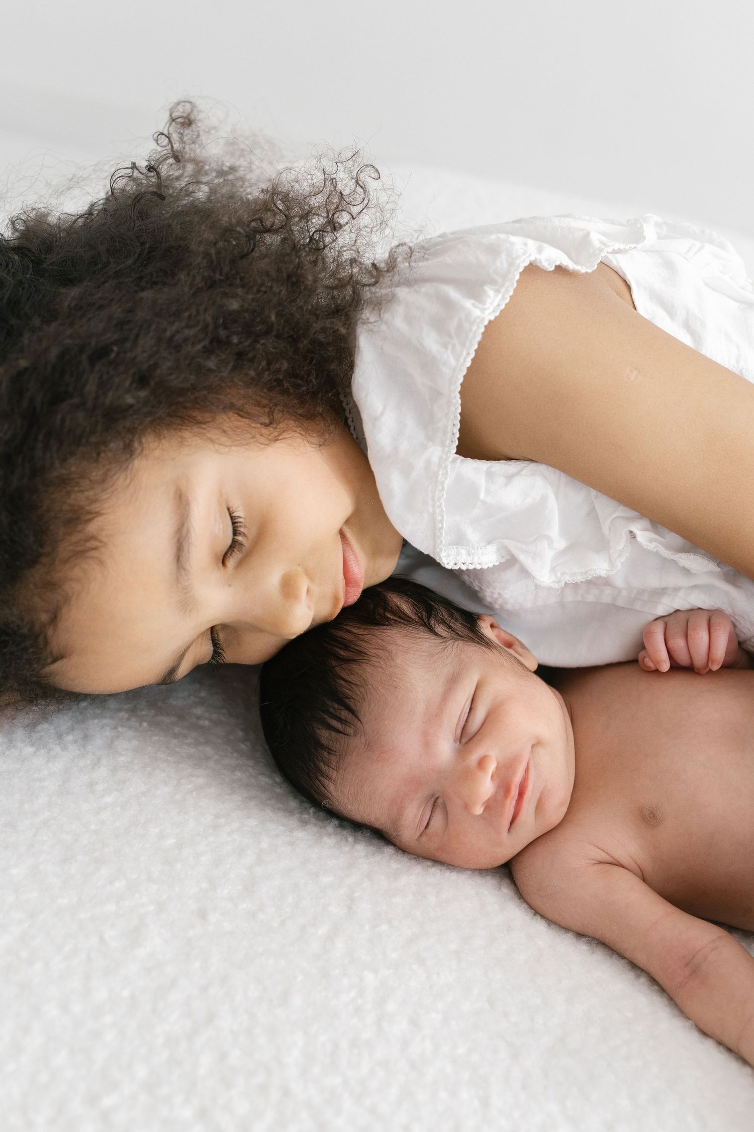 Peaceful series showing sleeping child under white covers on textured surface.