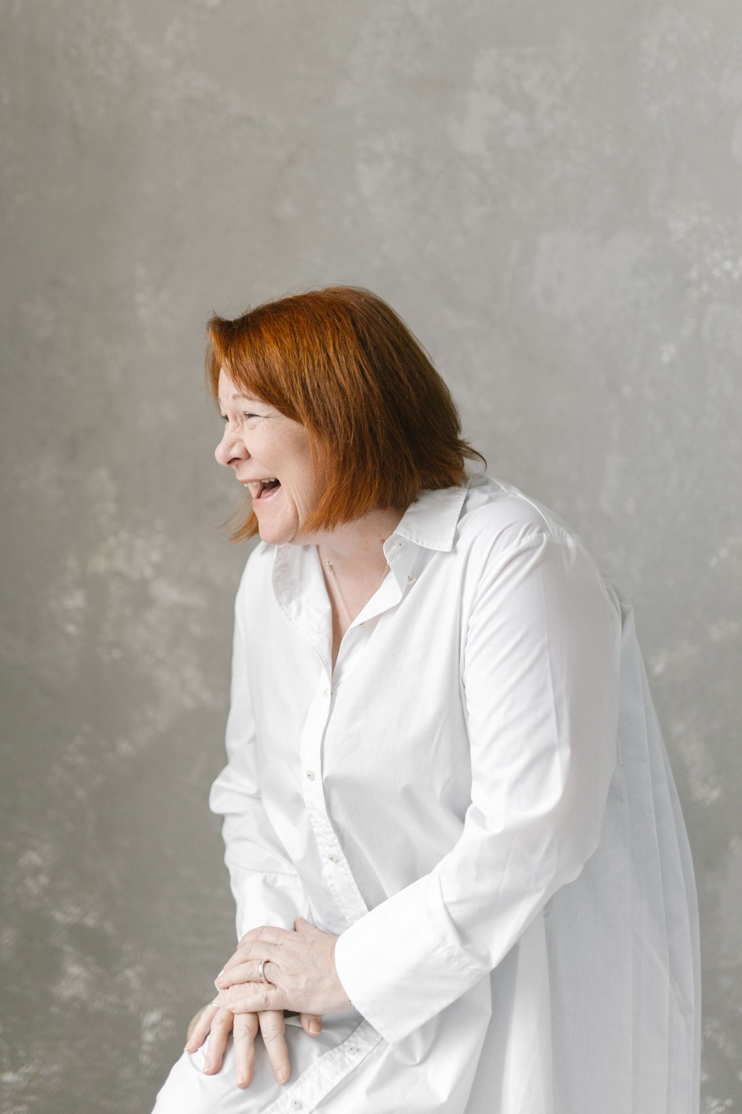 Candid portrait series showing joyful expressions in a white shirt against grey background.