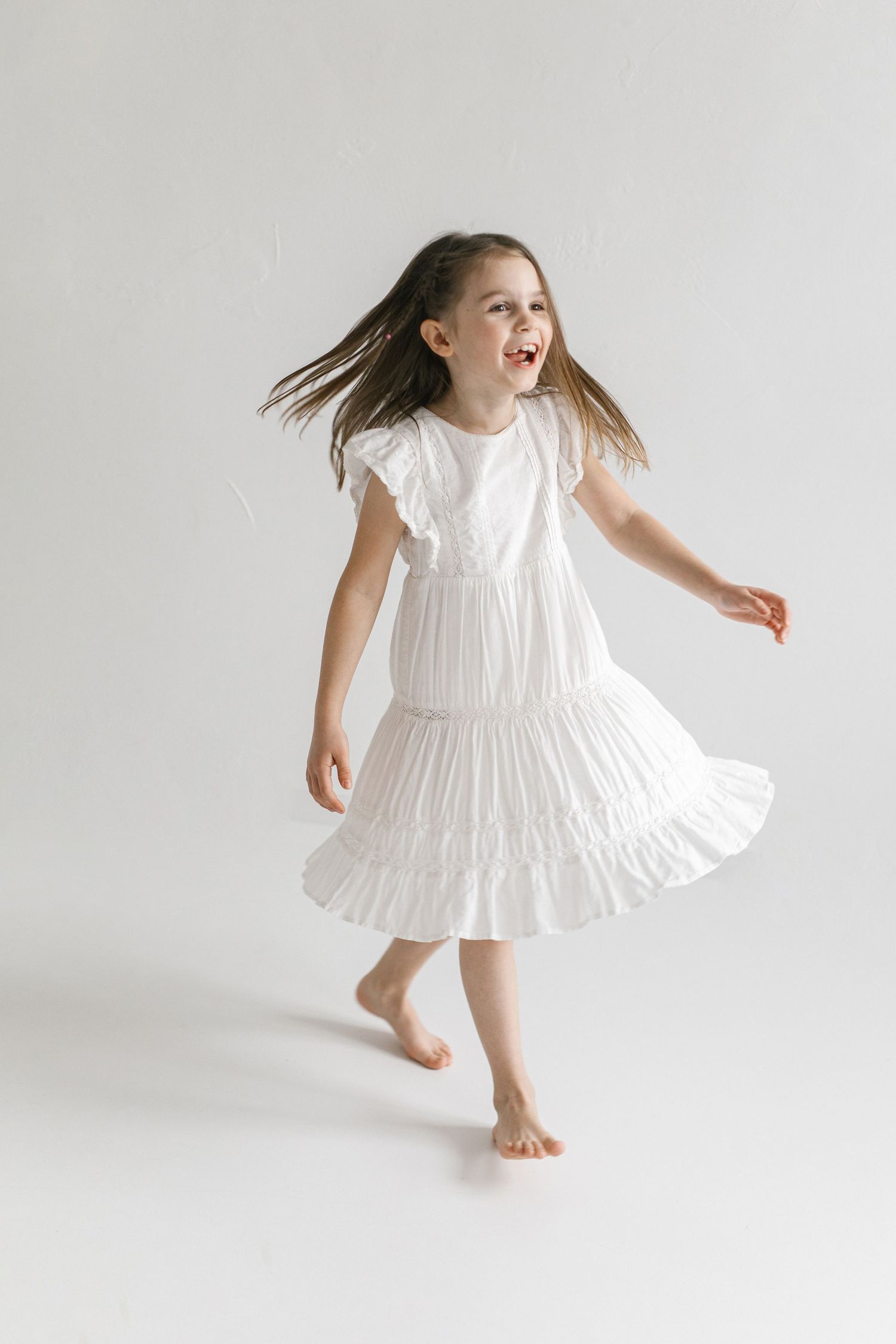 Dancing and twirling sequence in a flowing white dress against minimalist background.