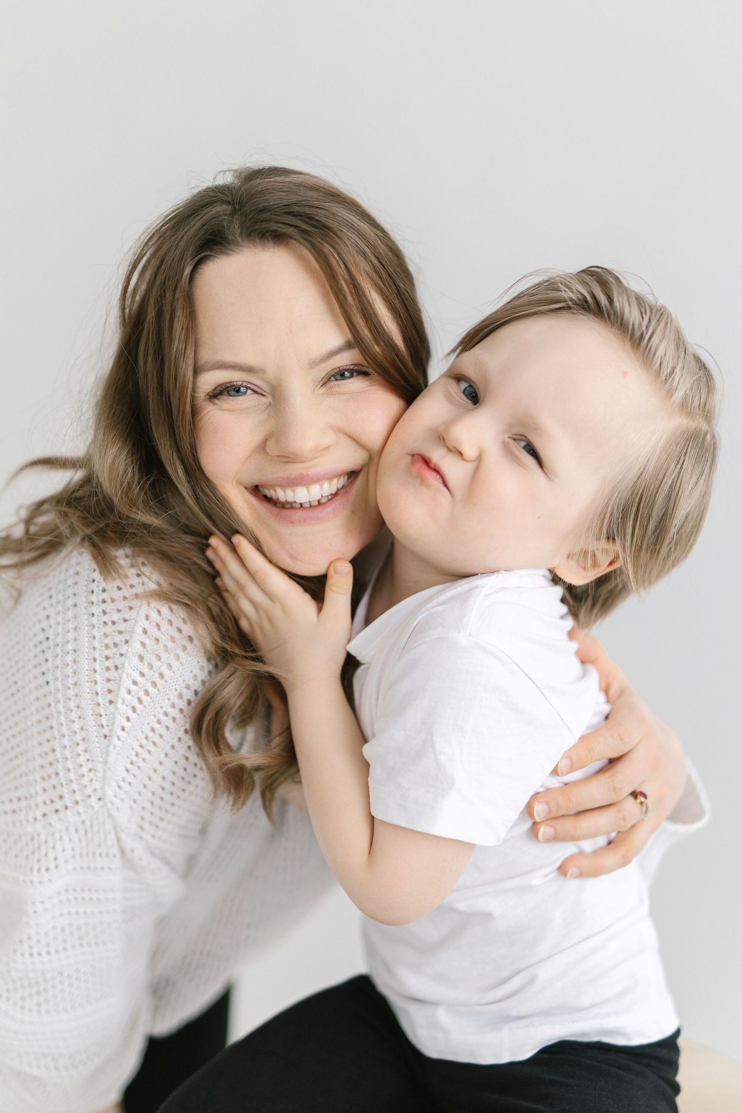 A heartwarming series of candid moments showing playful interaction between two people in white against a light background.